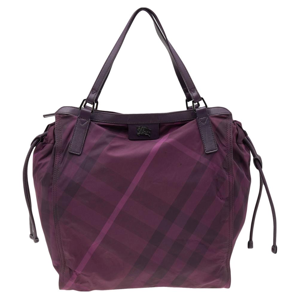 Burberry's Buckleigh tote delivers the best of convenient fashion. It is crafted from leather and check nylon, featuring dual top flat handles and a zip closure. This tote has a nylon-lined interior and drawstrings on the sides