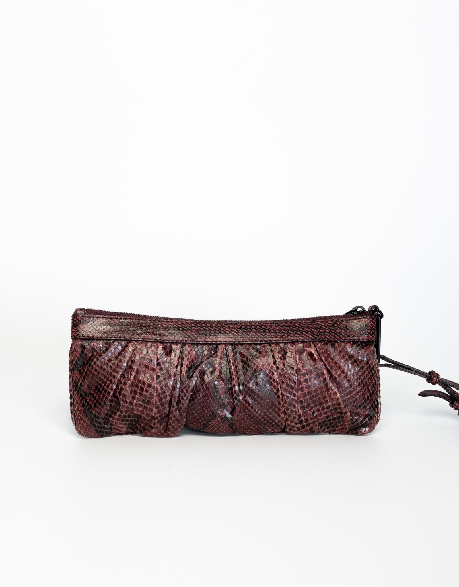 This clutch by Burberry is made of dyed snake skin and features a black top zipper closure, a snake skin strap and a cloth interior.

COLOR: Purple
MATERIAL: Python
ITEM CODE: ITEFFEPI14SCA
MEASURES: H 4.5” x L 11.5” x D 0.75” 
COMES WITH: Tags,