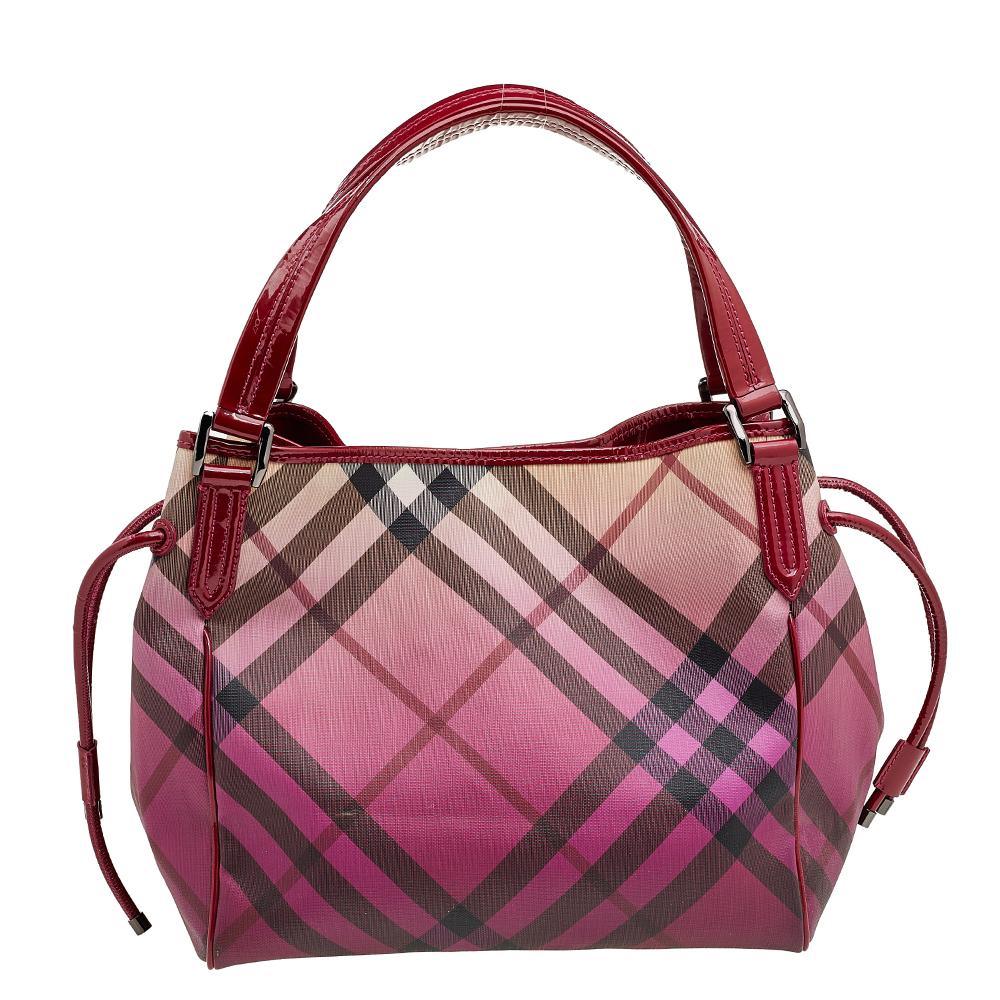 This Bilmore tote from Burberry will charm its way into your wardrobe effortlessly. It has been made using Raspberry Gradient Supernova Check coated canvas and patent leather with gunmetal-toned hardware used to complete its fittings. It has dual
