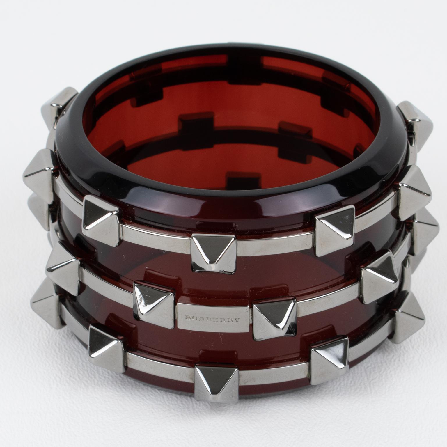A gorgeous original Burberry massive acrylic and metal bangle bracelet. 
Burberry revisits the punk cuff design in a chic and couture version. Chunky shape with maroon-red Perspex or acrylic bracelet sets with chrome metal rings and spikes. The