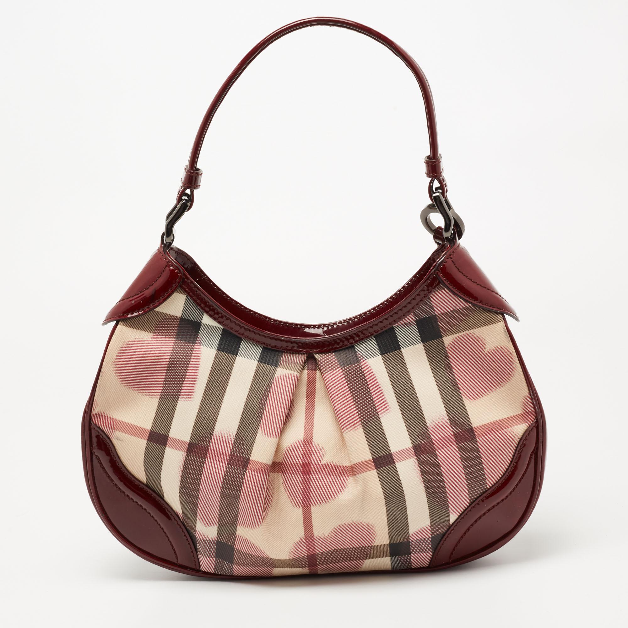 The Brooklyn hobo by Burberry is an everyday-friendly handbag. It is crafted from House Check Heart PVC and patent leather. This hobo features a top zip closure, a canvas-lined interior, and a single handle.
