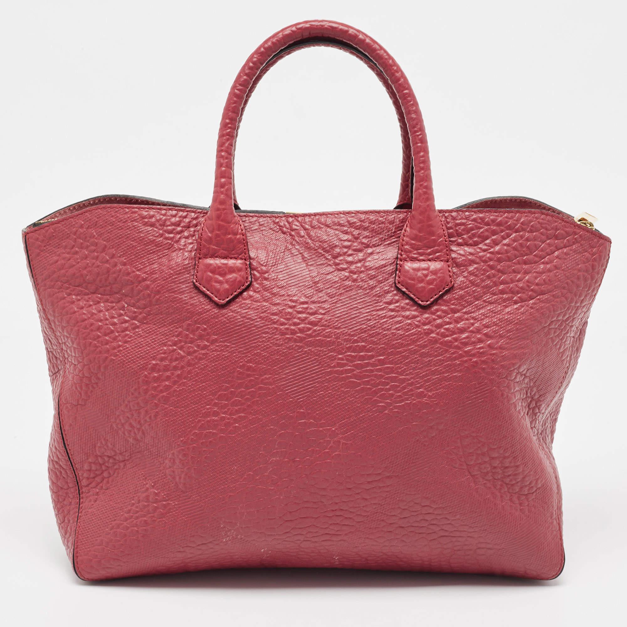 Add an essence of style and chicness to your look, flaunting this opulent Dewsbury tote by Burberry. Crafted from red leather, it features dual top rolled handles along with the shoulder strap and a brand logo at the front. The zip enclosed
