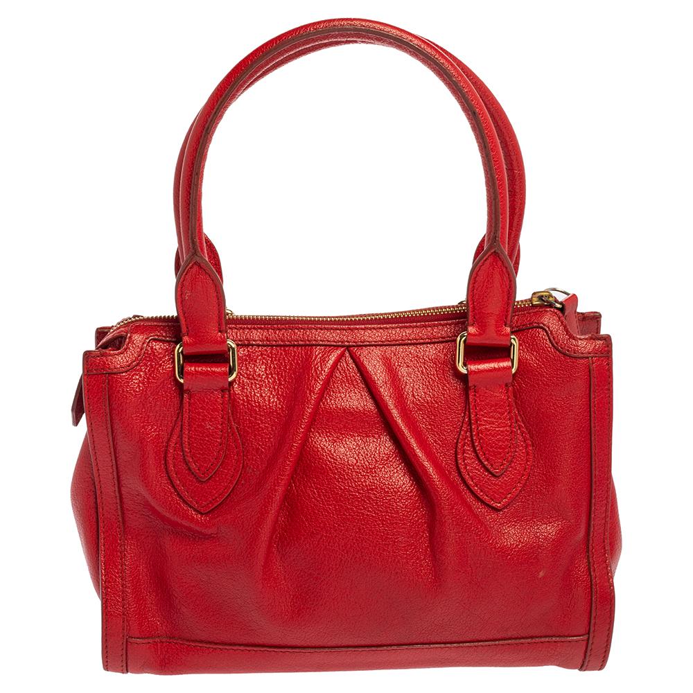 Look stylish when you hold this contemporary satchel by Burberry. Crafted from leather in red color, the creation features dual handles and a gold-tone logo plaque on the front. The zipper closure opens to a spacious interior, perfectly sized for