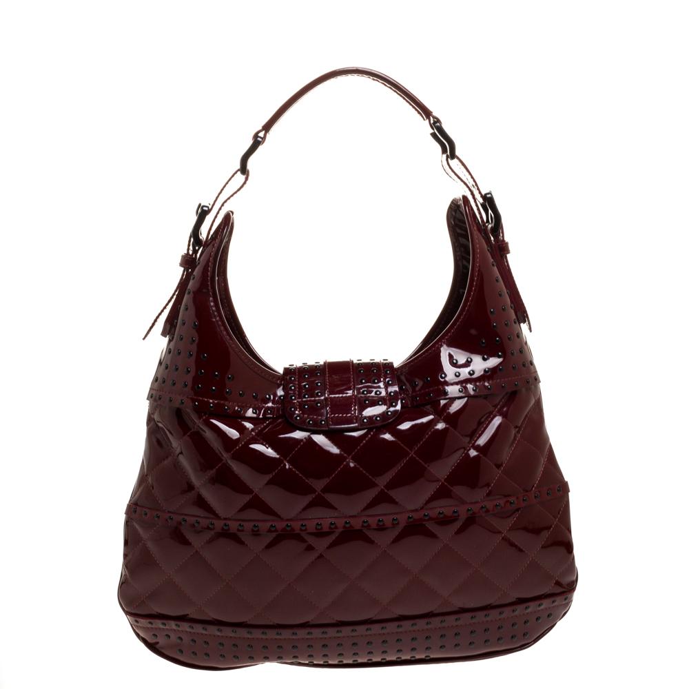 Catch admiring glances when you swing this Brooke hobo by Burberry. Crafted from patent leather, it is styled with studs and quilting. The buckle flap closure opens to a spacious nylon-lined interior that is capable of holding all your essentials