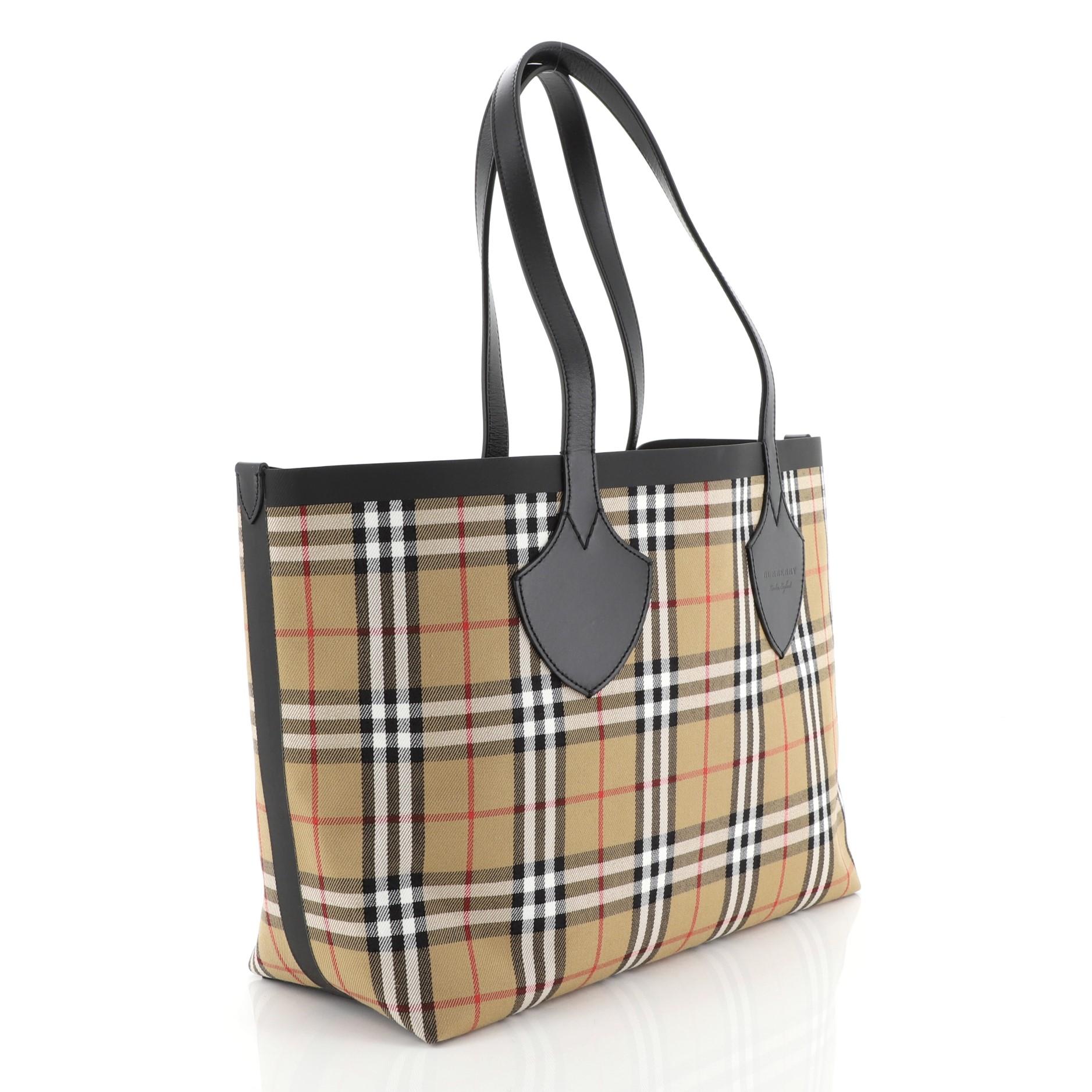 This Burberry Reversible Giant Tote Vintage Check Canvas Medium, crafted from neutral check canvas, features dual leather handles and trim. It opens to a reversible printed canvas. 

Estimated Retail Price: $1,150
Condition: Very good. Stains on
