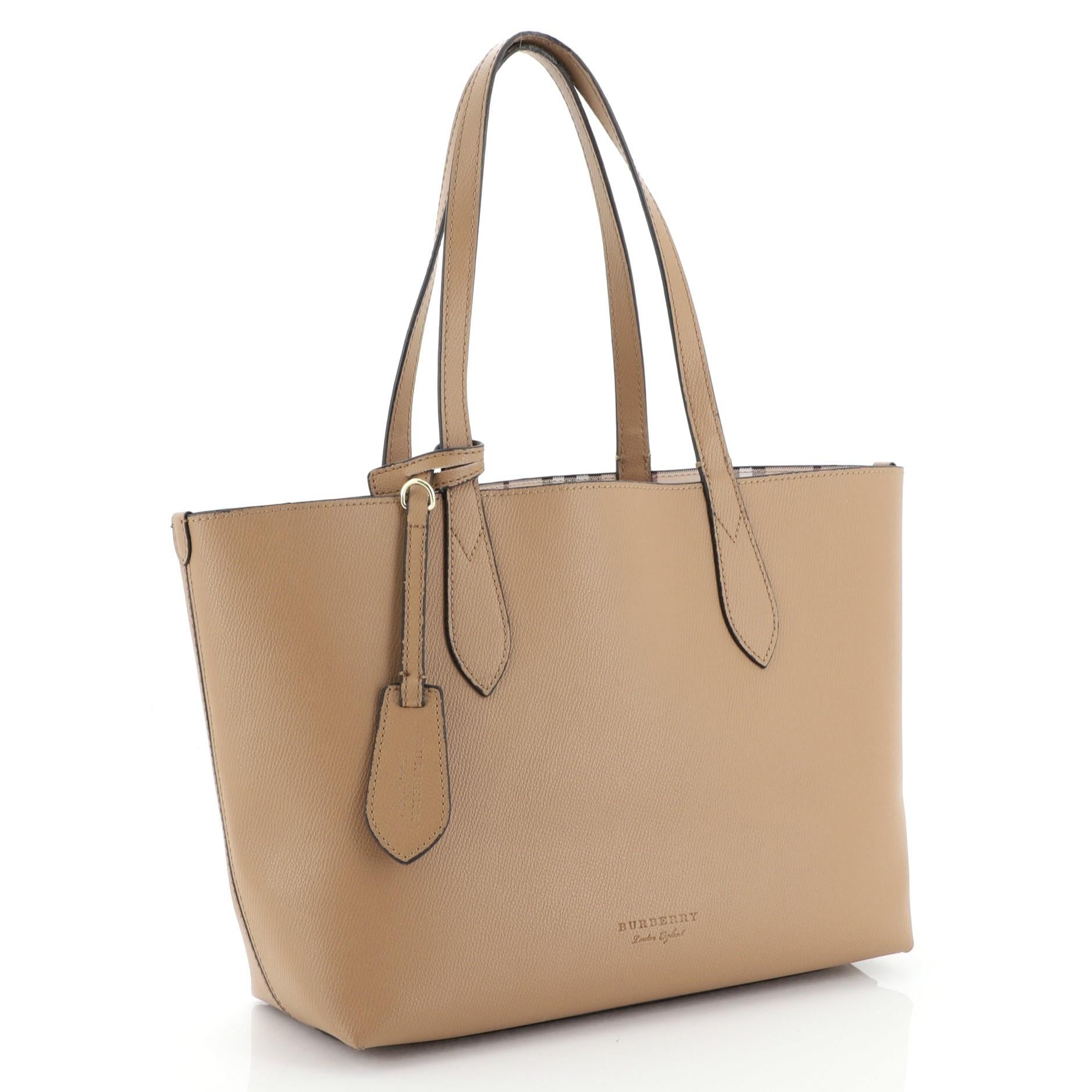 This Burberry Reversible Tote Haymarket Coated Canvas and Leather Small, crafted in neutral printed coated canvas and leather, features dual flat leather straps and gold-tone hardware. Its wide open top showcases a reversible neutral printed coated