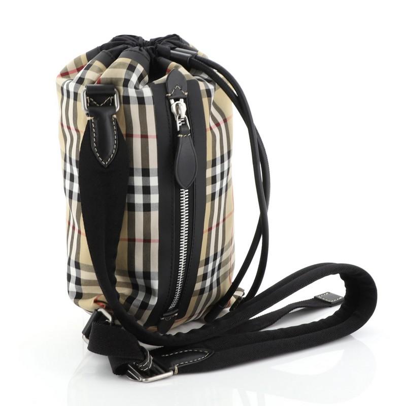 This Burberry Sailing Duffle Sling Bag Vintage Check Canvas Small is an everyday bag with a compact and functional design. Crafted from black and brown printed canvas, this bag features an adjustable strap, exterior front zip pocket and matte