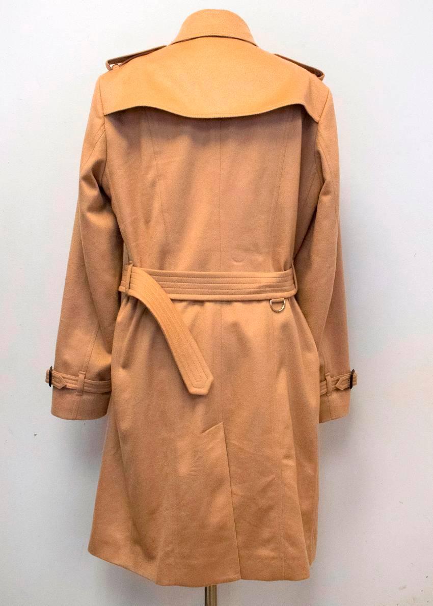 Burberry 'Sandringham' tan cashmere trench coat. This coat has a wide notch lapel and is double breasted with buttons down the center. This jacket is partially lined and ties at the waist. There are button pockets on each side at the front. The
