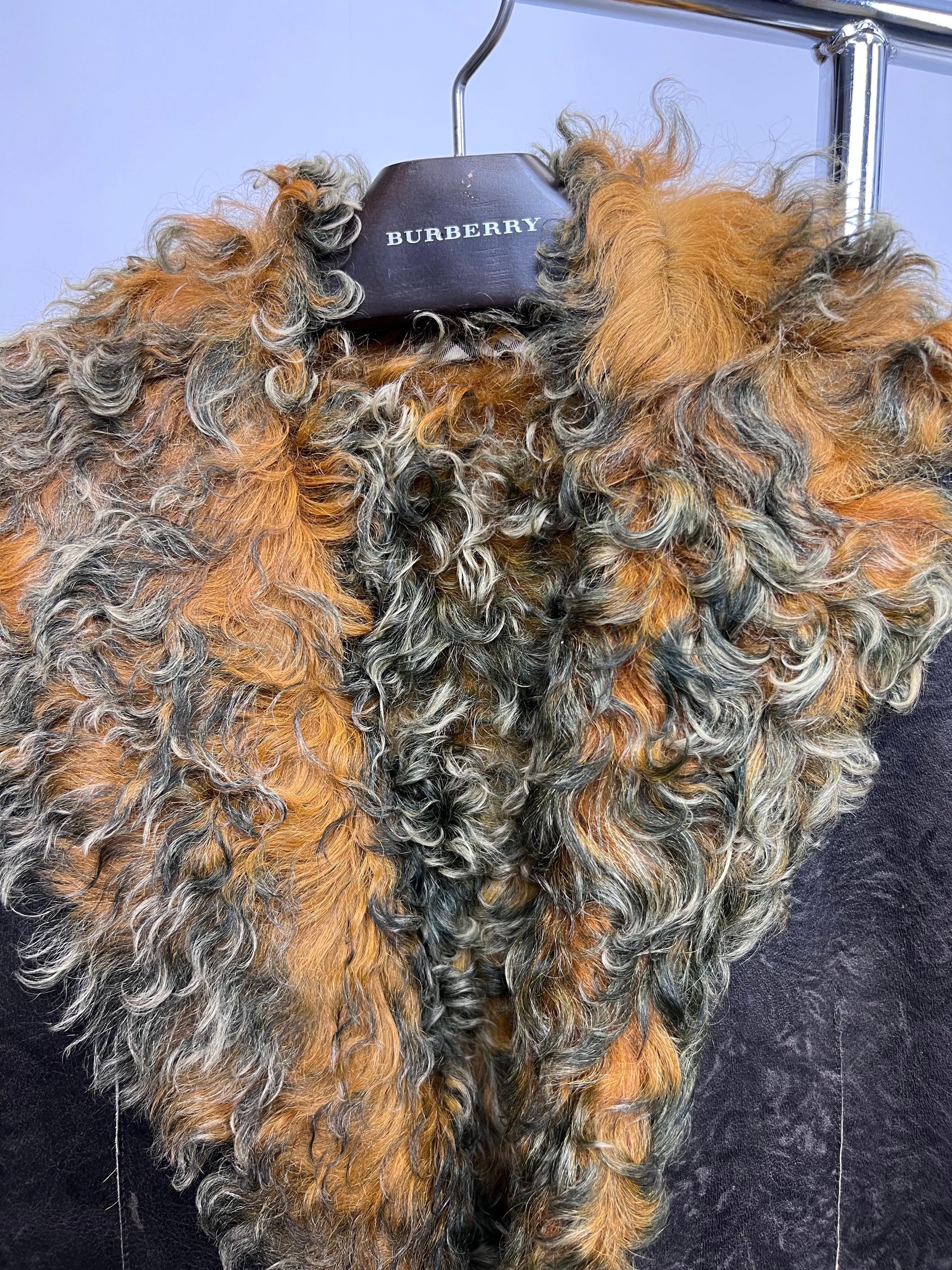 A timeless and luxurious Burberry shearling coat, expertly crafted from sumptuous brown leather with plush curly lamb fur lining for ultimate warmth and sophistication. This longline design features classic tailoring with a structured silhouette,