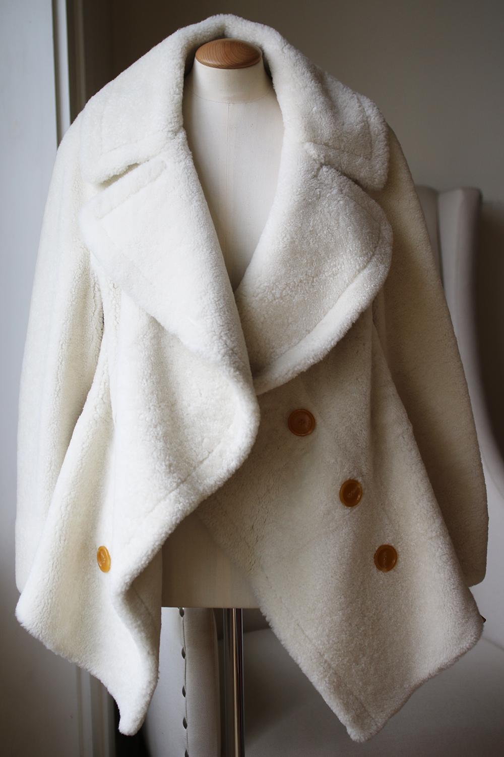 This Burberry's coat is inspired by the curved lines of Henry Moore's sculpture, It's made from thick, cozy cream shearling and has an oversized collar that falls into a softly draped front with a cotton-blend cable-knit back creates a