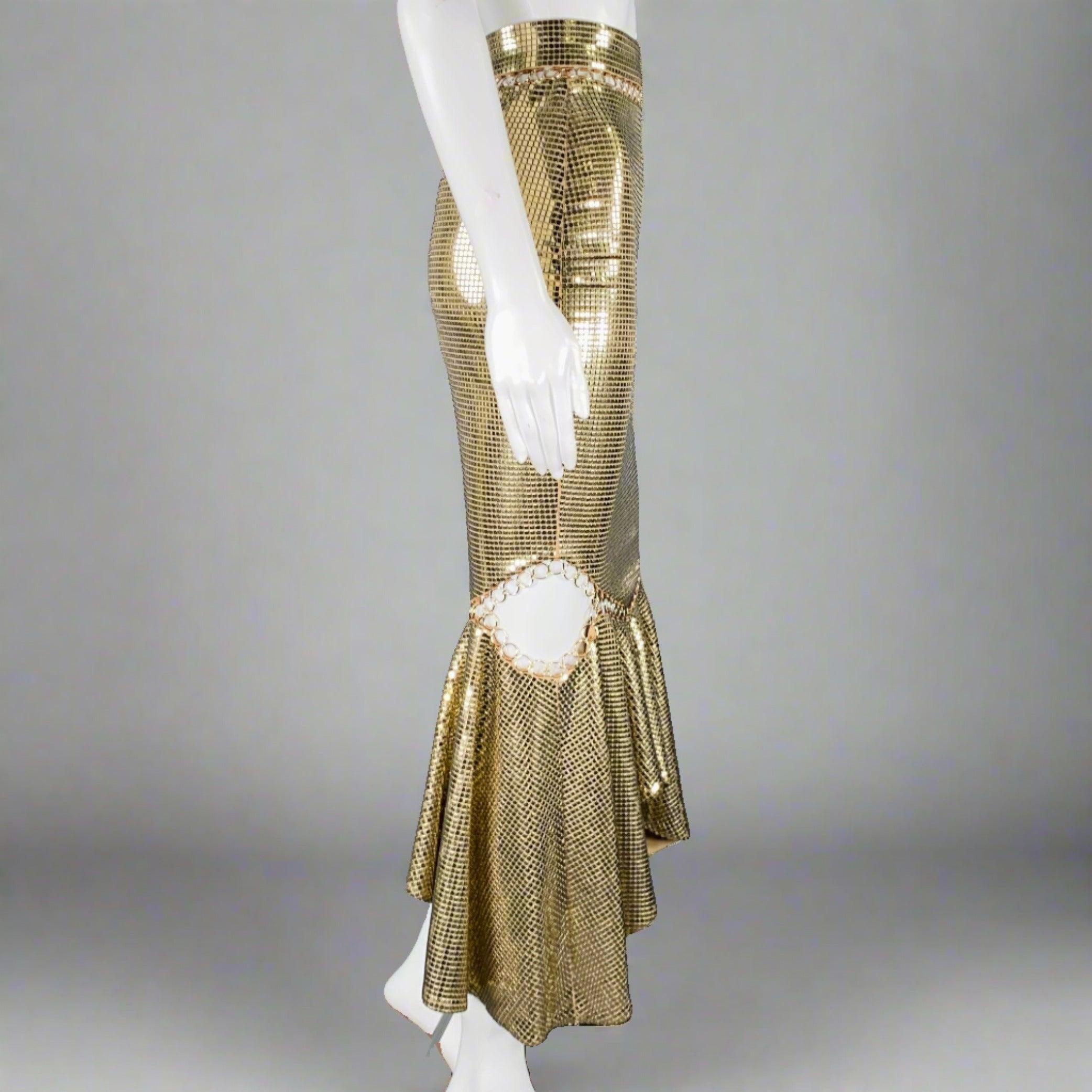 BURBERRY by RICARDO TISCI skirt
in a gold and beige viscose blend fabric featuring a mermaid style, all over mirror tile embellishment, peekaboo ring details, and side zipper closure.Very Good Pre-Owned Condition with Tags. Signs of wear on some