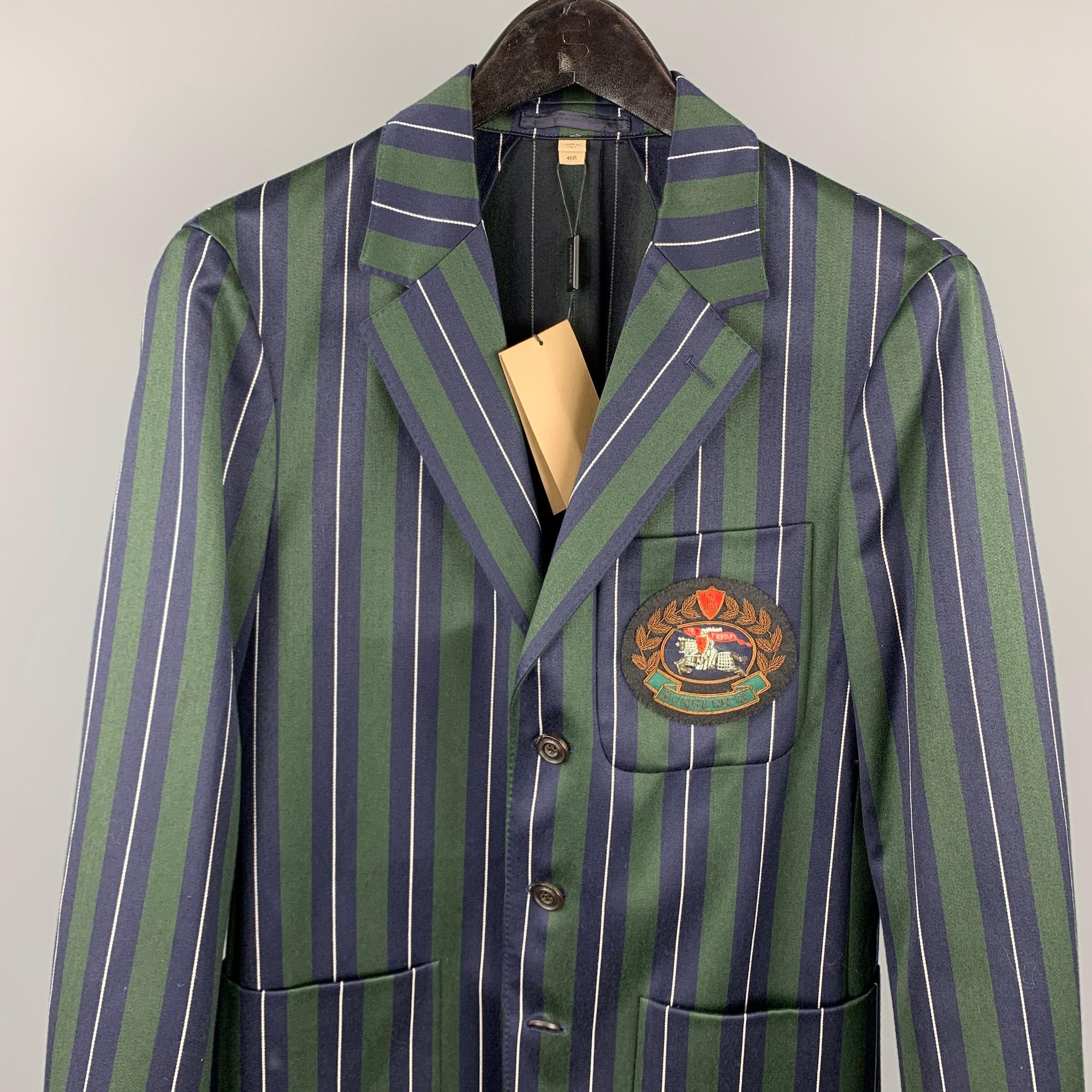 BURBERRY suit comes in a green & navy vertical stripe wool / cotton with a half liner and front embroidered patch featuring a single breasted, three button sport coat with a notch lapel and matching flat front trousers. Made in Italy.

New With