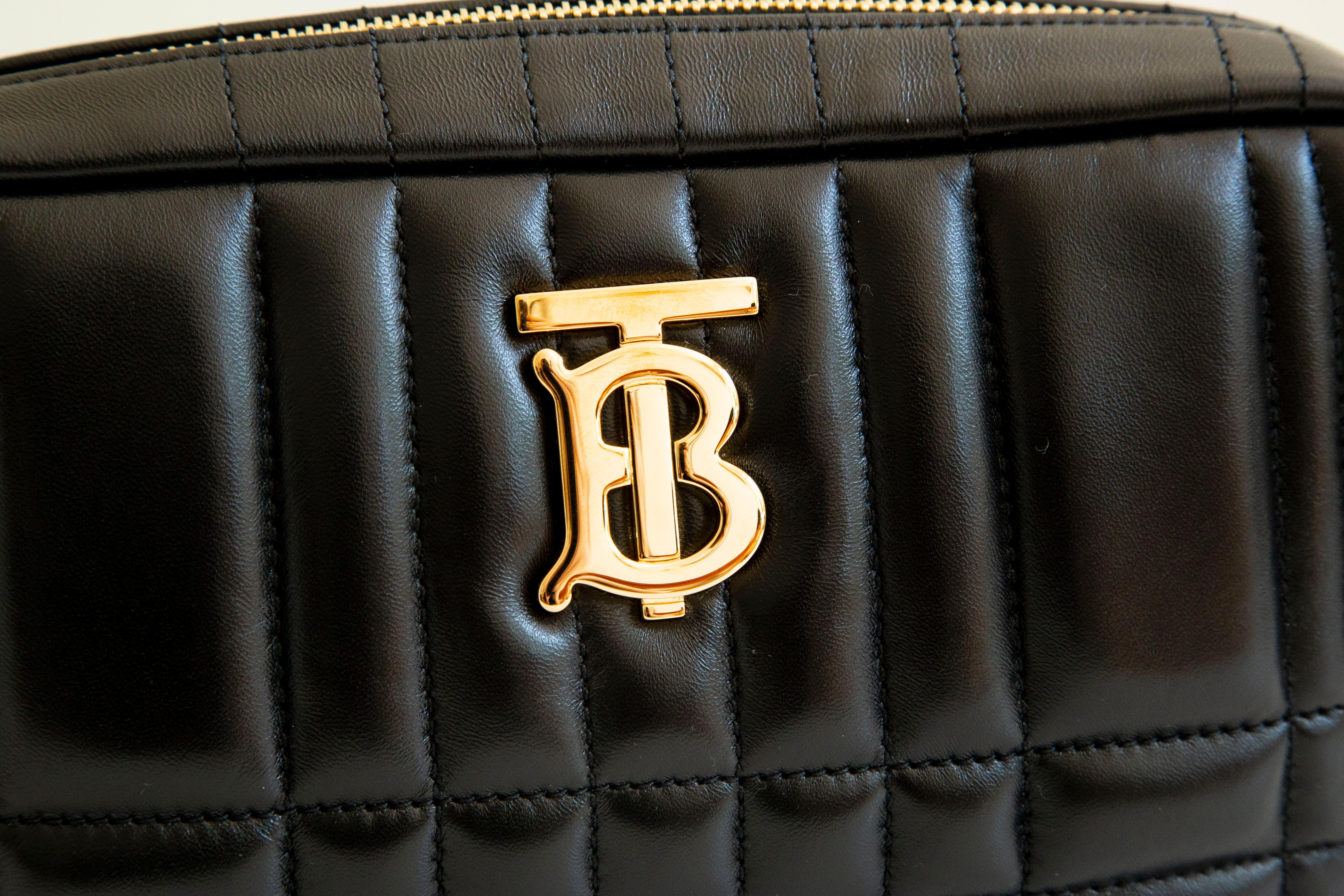 An authentic Burberry Small Lola camera bag, shoulder bag, crossbody bag. The bag features a soft calfskin black leather exterior and gold-toned hardware. The interior is lined with black fabric and there is one slip pocket inside. The interior,