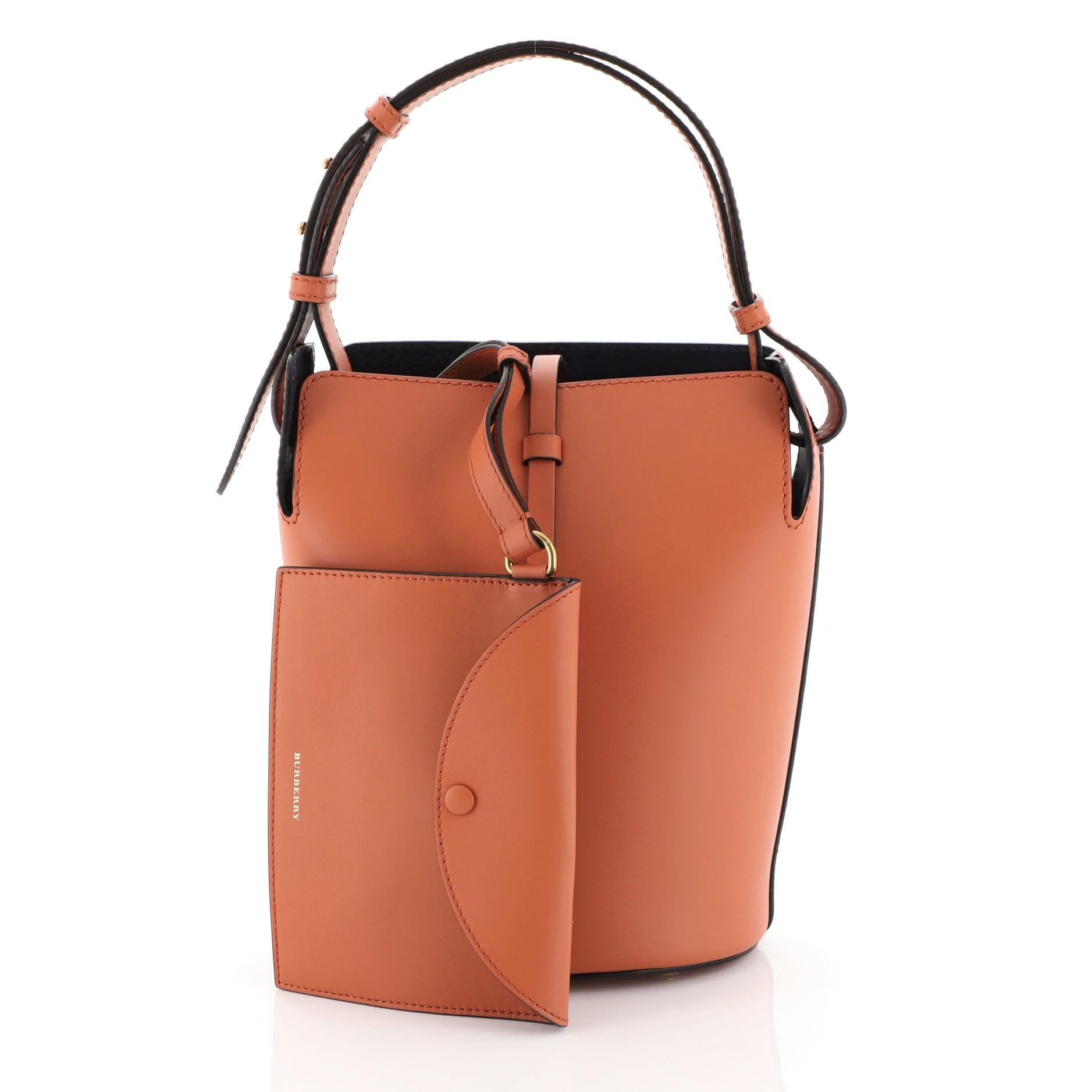 This Burberry Supple Bucket Bag Leather Medium, crafted from orange leather, features adjustable flat shoulder strap and aged gold-tone hardware. It opens to a blue leather interior.

Estimated Retail Price: $1,890
Condition: Excellent. Minor