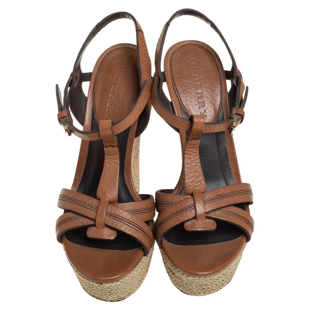 Simple, elegant, and comfortable, these tan Burberry sandals will make a fine addition to your shoe collection. They are styled with ankle straps, buckle fastenings, and espadrille wedge heels. These beautiful leather sandals are a perfect option