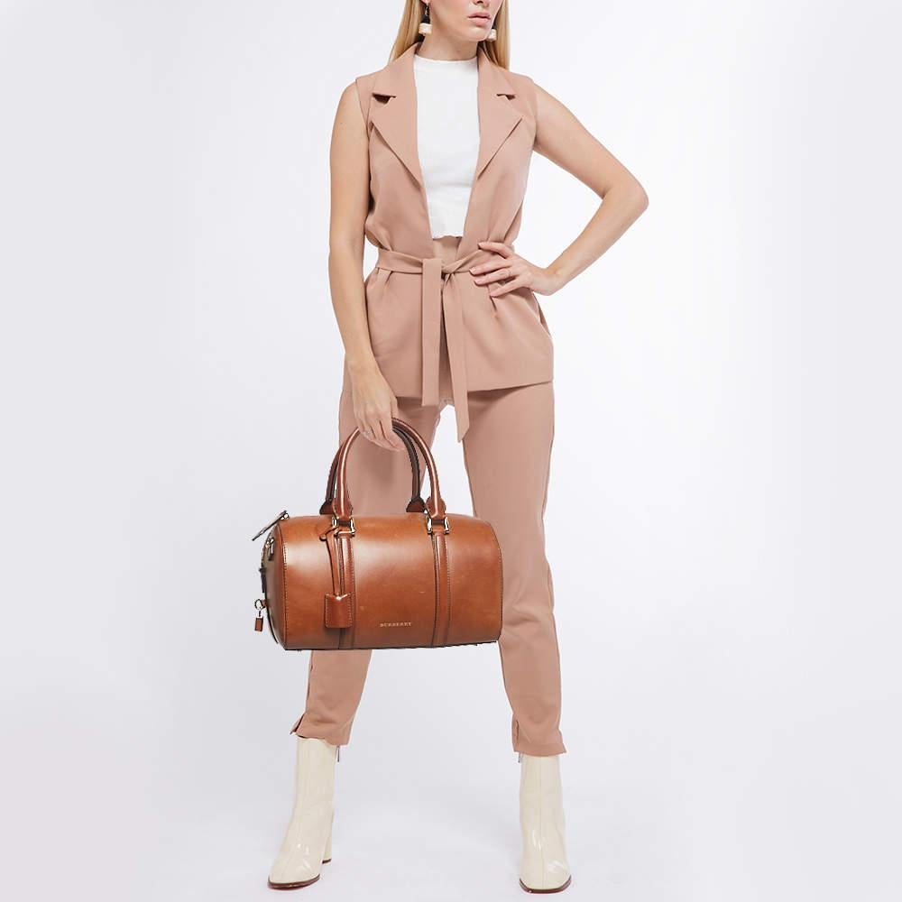 A stunning blend of elegance and luxury, this Burberry bag is an instant classic. Ideal for your daily use, this barrel-shaped bag has dual handles for easy carrying option. The gold-tone hardware perfectly complements this sleek creation.