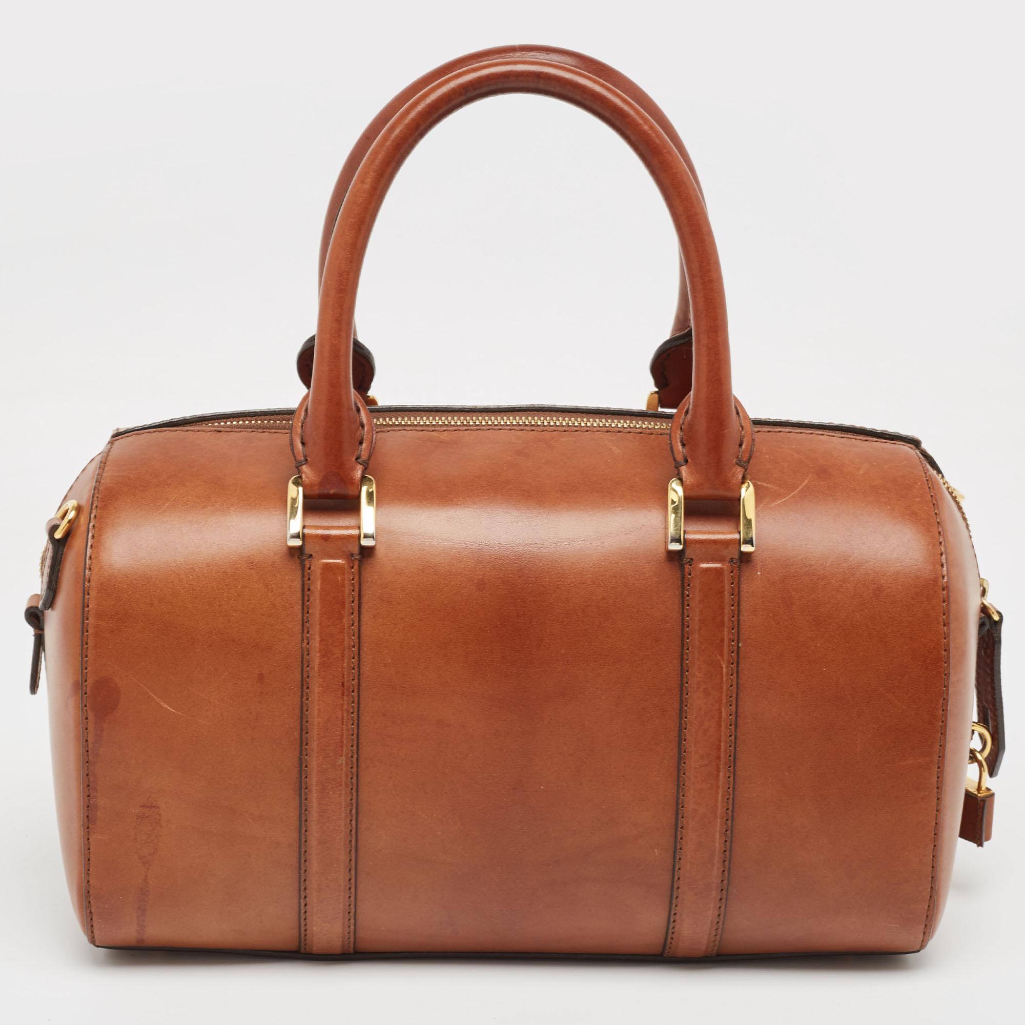 A stunning blend of elegance and luxury, this Burberry bag is an instant classic. Ideal for your daily use, this barrel-shaped bag has dual handles for easy carrying option. The gold-tone hardware perfectly complements this sleek creation.

