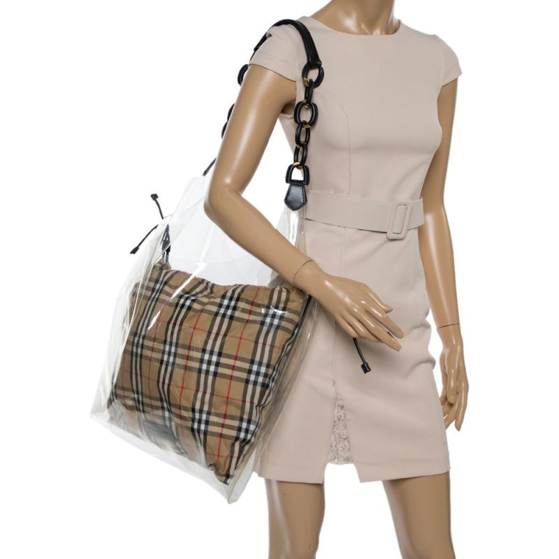 The perfect choice for special occasions, this Burberry shopper bag is true to its existence. Crafted from transparent plastic and leather, the exterior has a large expanse with a single shoulder strap. The signature checked interior that is visible