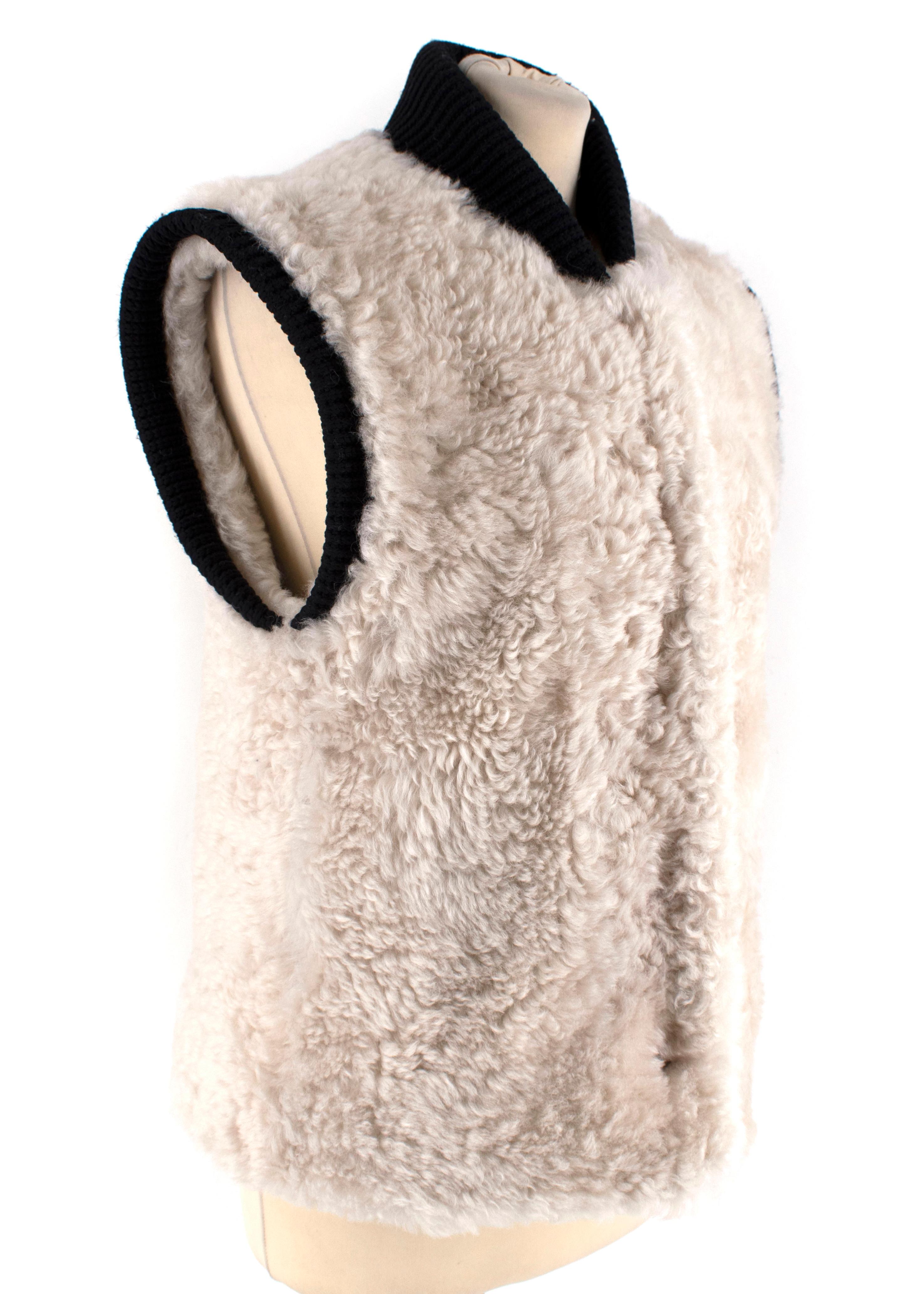 Burberry White Shearling Gilet

- Sleeveless design
- Hidden popper fastenings - High ribbed neck 
- Black ribbed trimmings
- Loose fit

Materials:
- 100% Shearling

Specialist Cleaning

Made in Italy 

Shoulders - 16cm
Sleeves - 24cm
Chest -