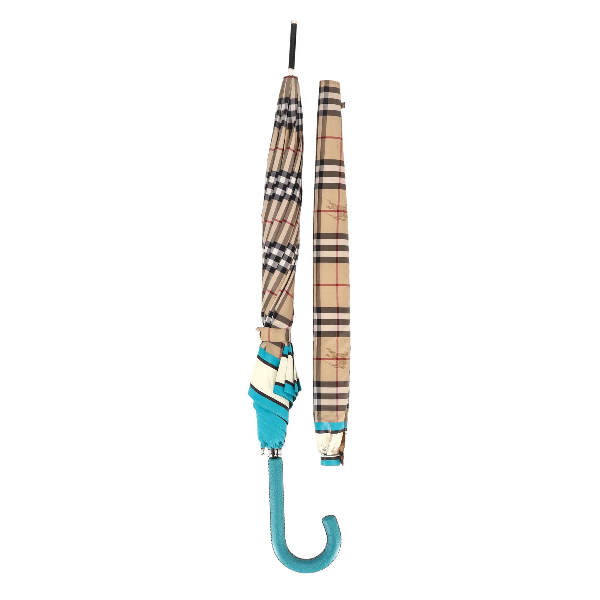 Burberry Vintage Check Umbrella With A Matching Cover

The brand’s signature Vintage Check pattern a beige base with black, red, and white plaid lines. 

Adorned with turquoise blue and cream border accents and a matching turquoise leather curved