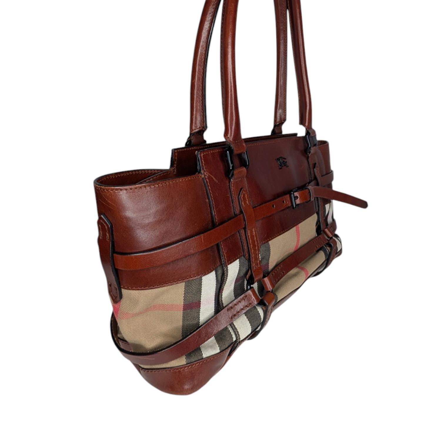 The house of Burberry has a knack for creating classic bags with a twist. This Burberry Dark Tan Bridle House Check Canvas Satchel Bag features belted details that create an effortlessly stylish look that will elevate any look. We love the contrast