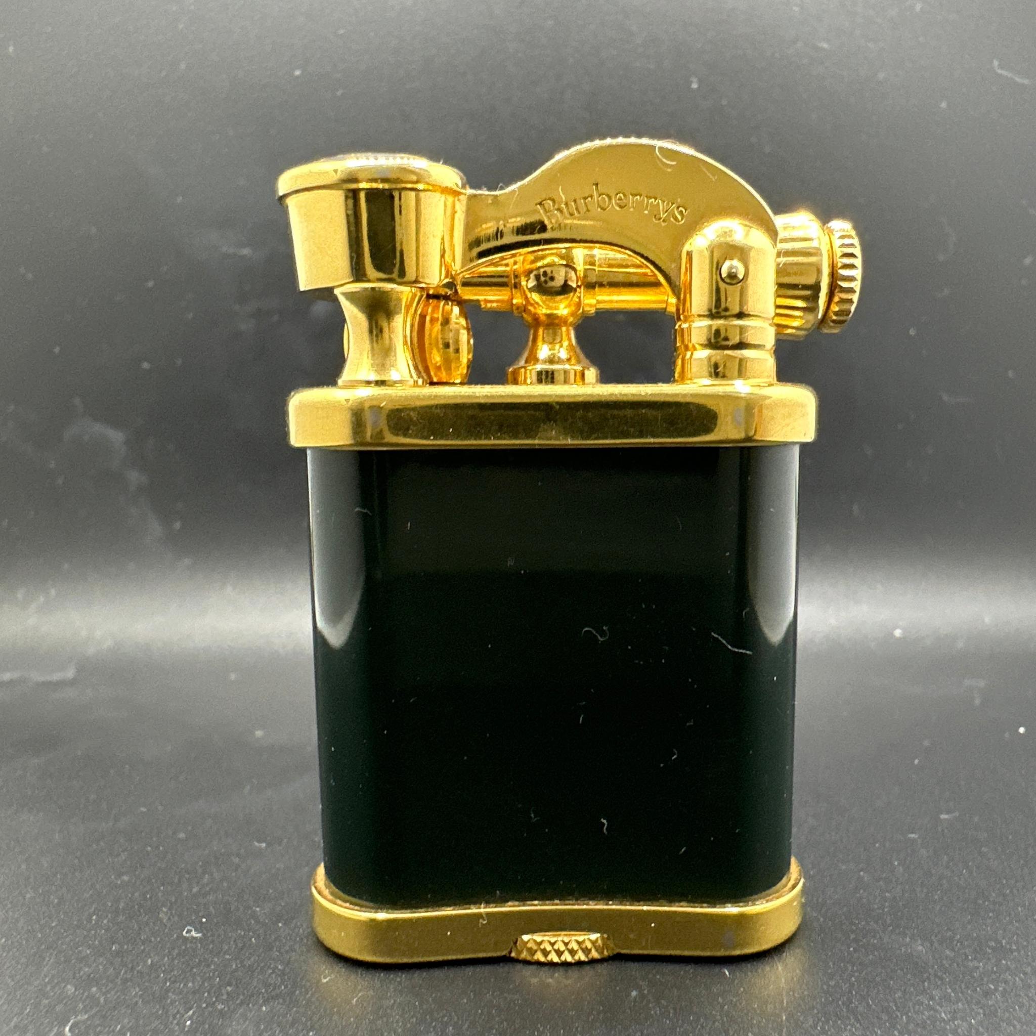 Burberrys BRITISH dark green enamel gold plated lighter with blue sapphire cabochon.
It is in mint working condition. 
Comes with original Burberry box which is very rare. 
The interior of the box is imperial British blue velvet. 

Burberrys lift
