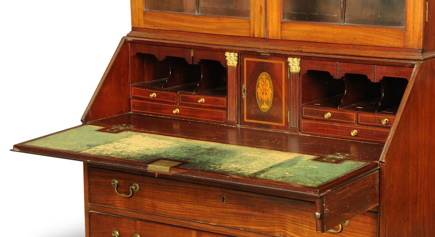 A George III mahogany bureau bookcase, with swan neck pediment above a pair of glazed doors with circular wooden astragals, satinwood banded fall front opening to a fitted interior and with four long graduated oak lined drawers with brass swans neck