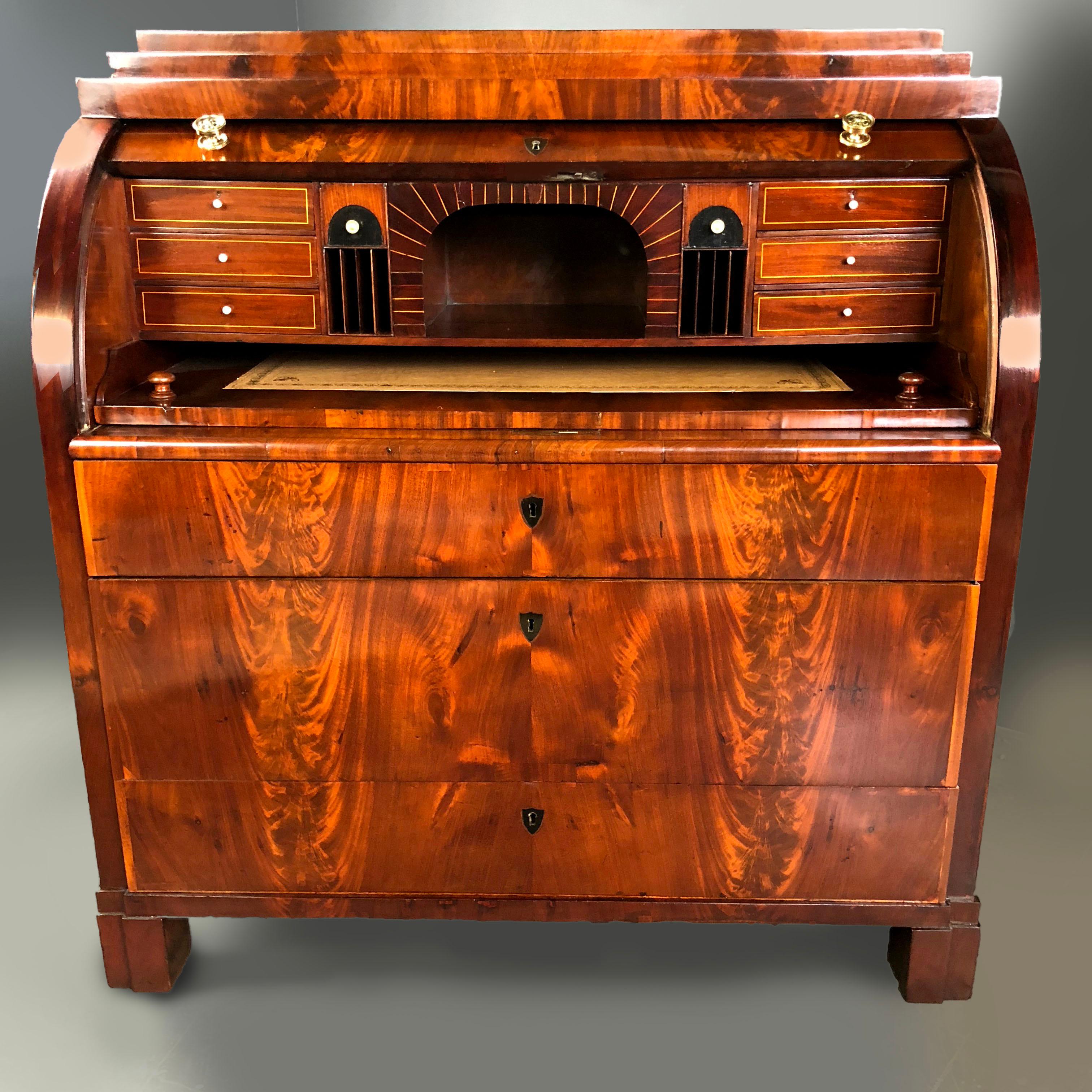 Early 19th century Biedermeier period Bureau of Danish origin of finely figured mahogany veneers, with a cylinder top that once open, it reveals a series of small drawers and hidden compartments, around a central open compartment. There is a writing