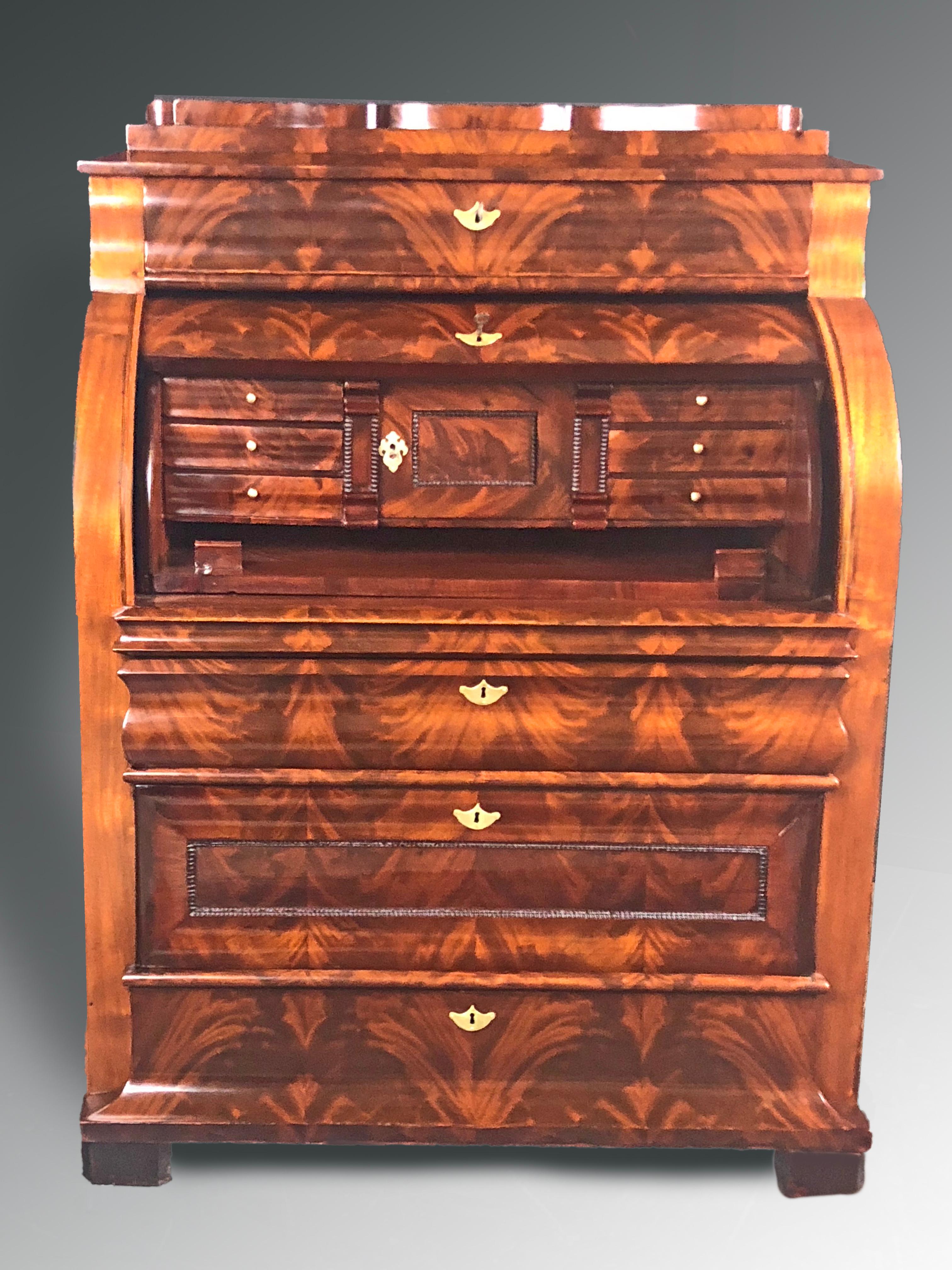 Outstanding Danish Biedermeier cylinder top Bureau dating to the mid-19th century with impressive crotch mahogany veneers. Once open, the cylinder top reveals a series of small drawers flanking a central locking cabinet and a writing surface that
