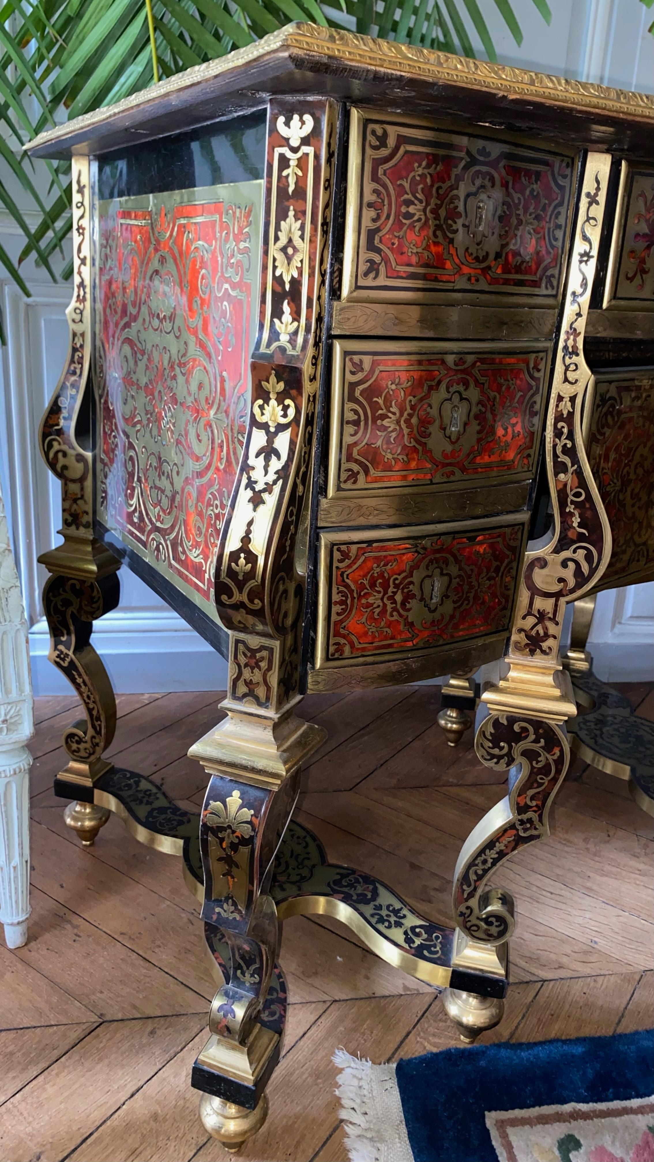 Bureau Mazarin en marqueterie Boulle. II riposa su huit pieds réunis par deux entretoises en X, montants à pan en décrochement. Plateau marqueté cerclé di una lingotière in bronzo ciselé e dorato con decori di palmette e foglie d'acanto.