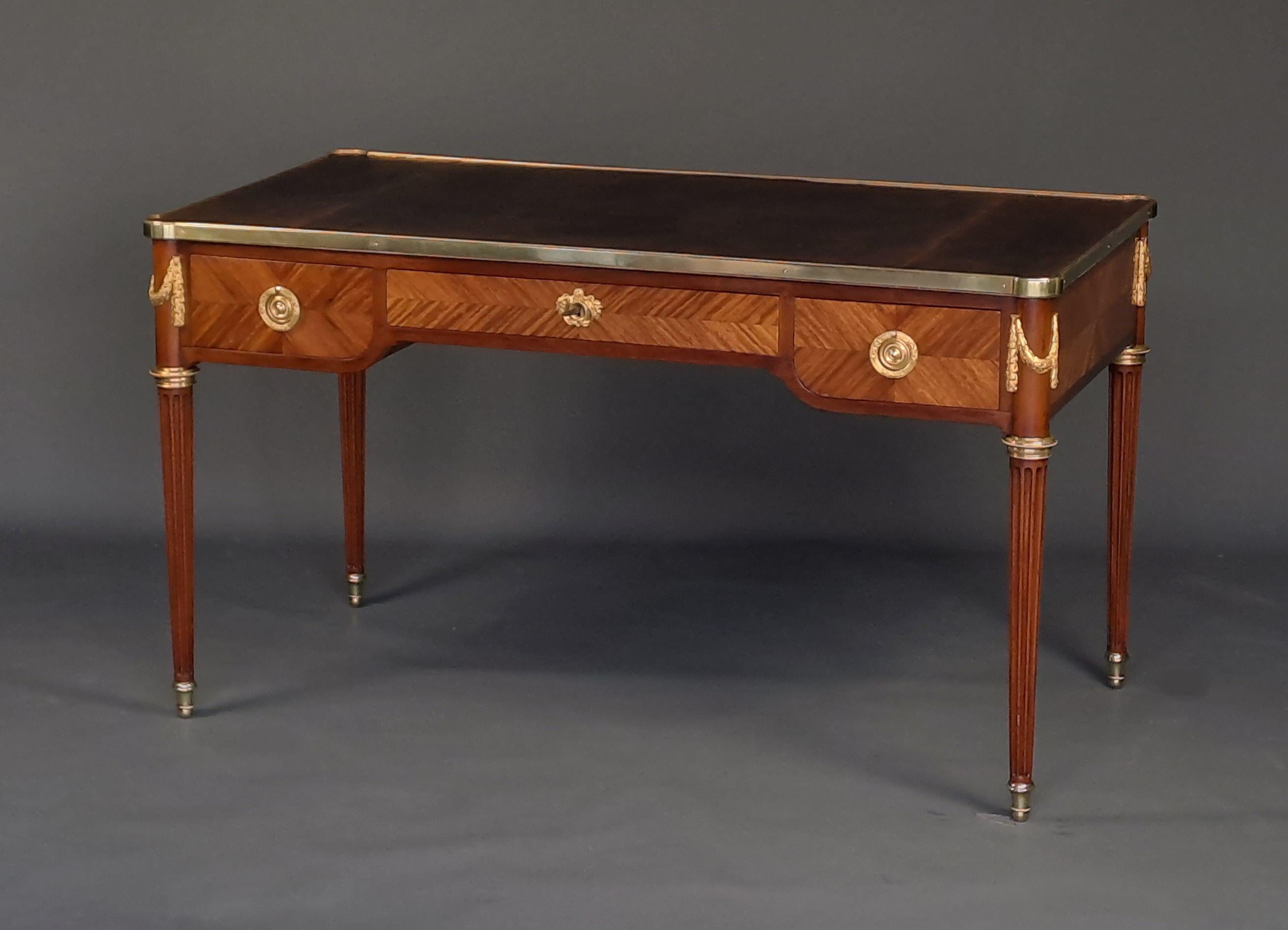 Elegant Louis XVI style Bureau Plat in mahogany and marquetry in rosewood frieze.

Beautiful ornamentation of very finely chiseled gilt bronze.

Moroccan leather top surrounded by a gilt bronze ingot mold.

Opening three drawers in