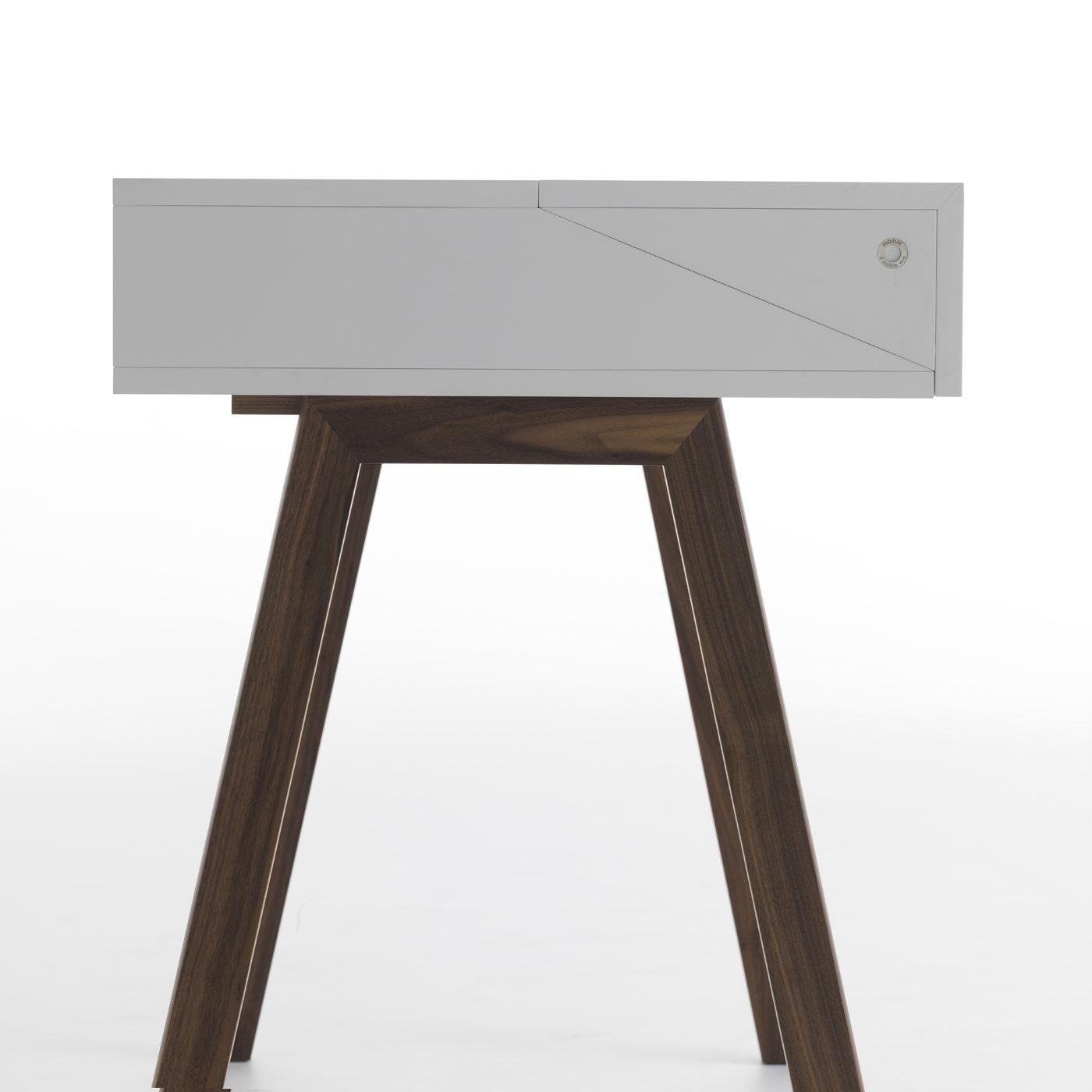 This modern piece of functional decor designed by Esa Vesman boasts a clean, elegant allure. Versatile and innovative, it stands on Canaletto walnut wood with a white-lacquer finish and features a hutch in MDF that flips open revealing a functional