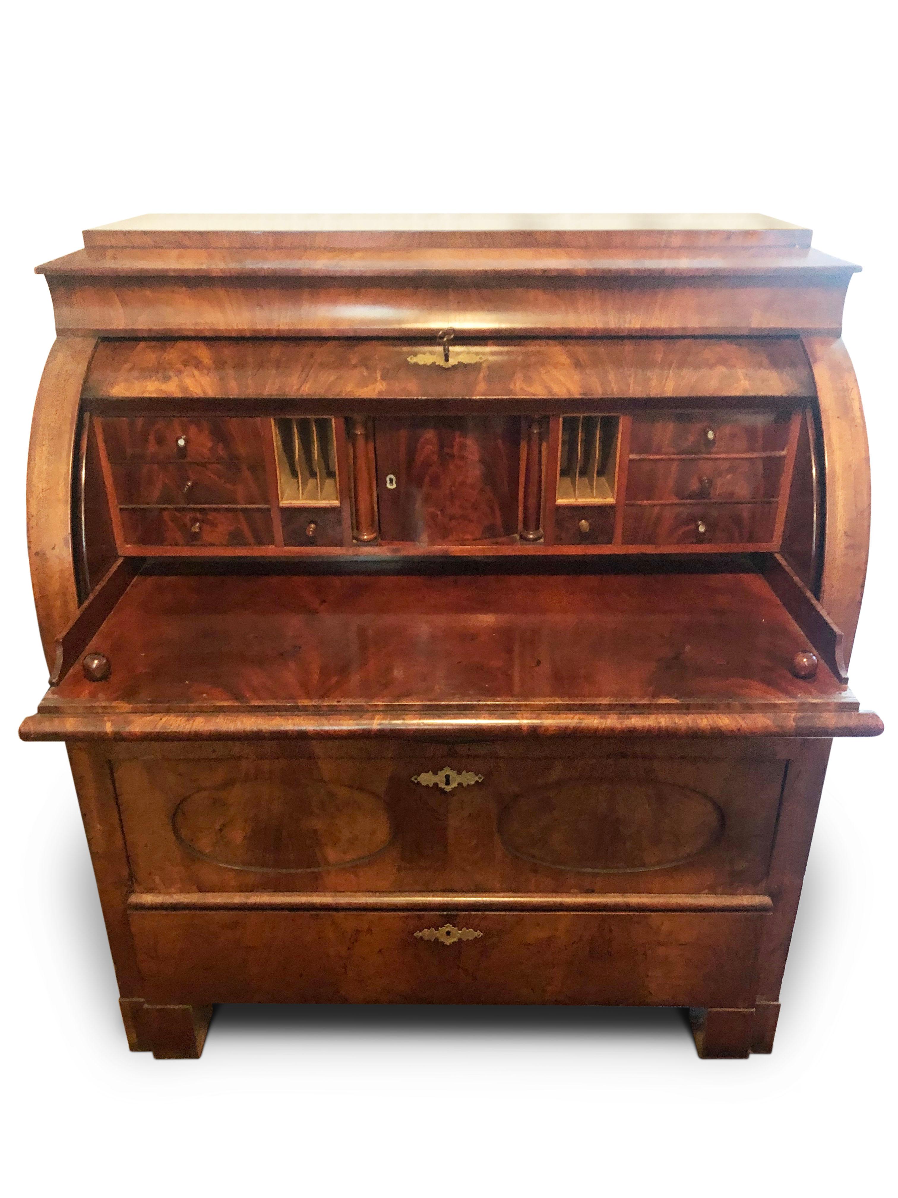 Bureau/writing desk walnut Biedermeier, circa 1840.

Roll top front, opening to a draw out sliding desk surface, with central cupboard flanked by two columns, pigeon holes and various drawers.
Three larger drawers beneath decorated with