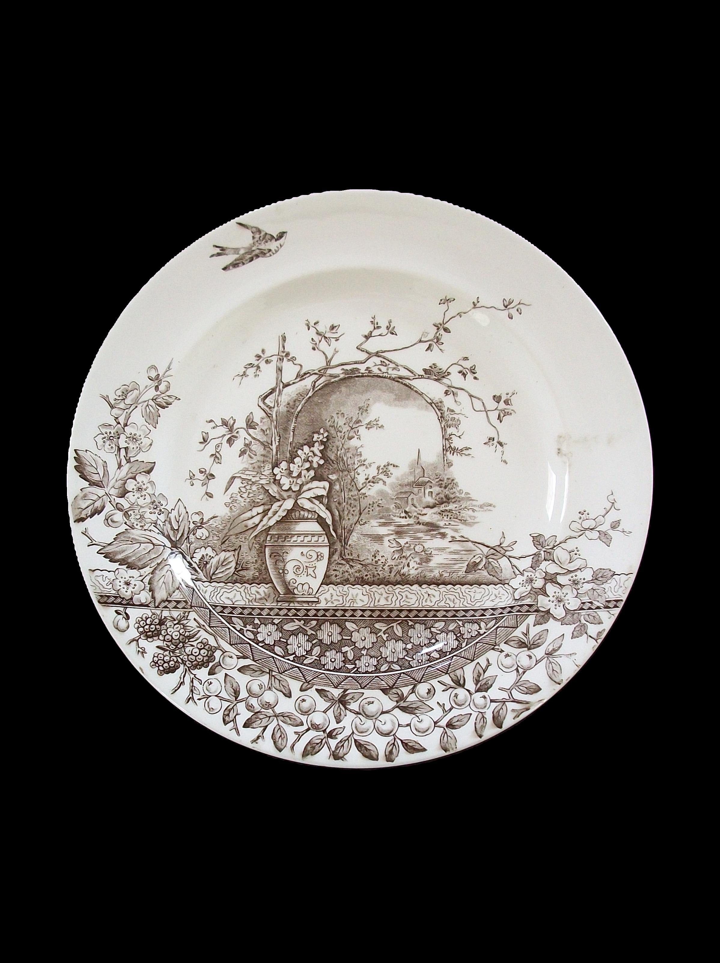 BURGESS & LEIGH - HILL POTTERY (Fabricante) - Rústico (Nombre del patrón) - Plato de cerámica para vitrina decorado por transferencia del Aesthetic Movement en marrón - con frutas, flores y una golondrina sobre un paisaje lejano - firmado en el