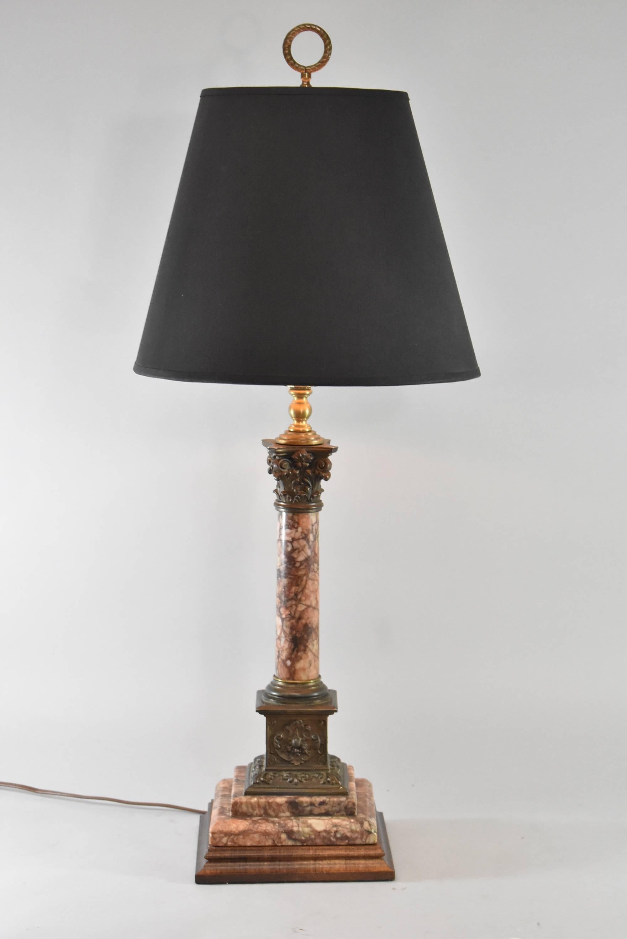 A beautiful marble table lamp. It features a lovely burgundy and grey marble in a pillar form with bronze scroll details and a wood base. Very good condition. The dimensions are 30.25