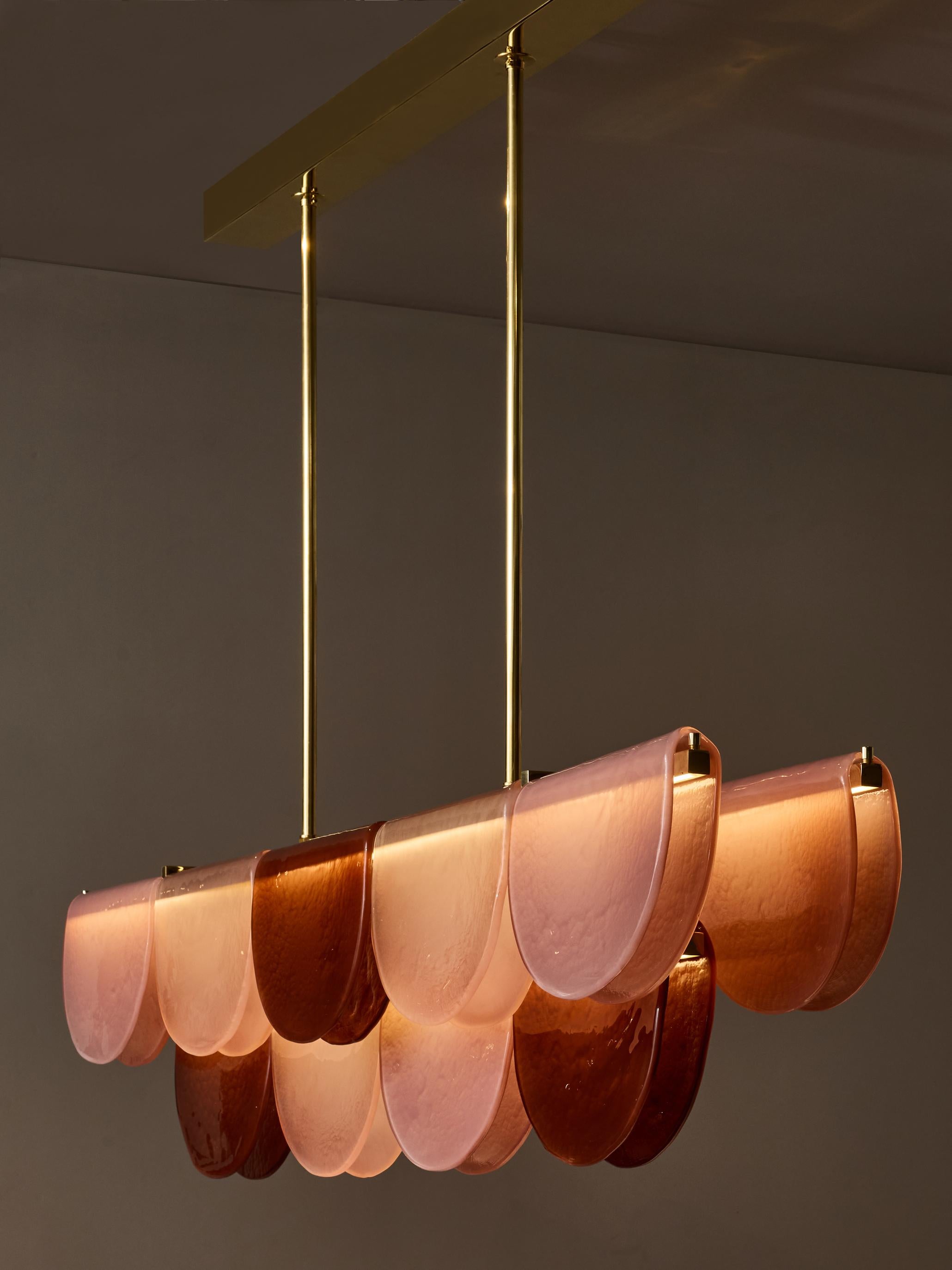 Long chandelier made of a brass structure with three levels, enlightened with LED strips running all the length. Each level is covered with Murano glass plate as if it was folded around the structure.