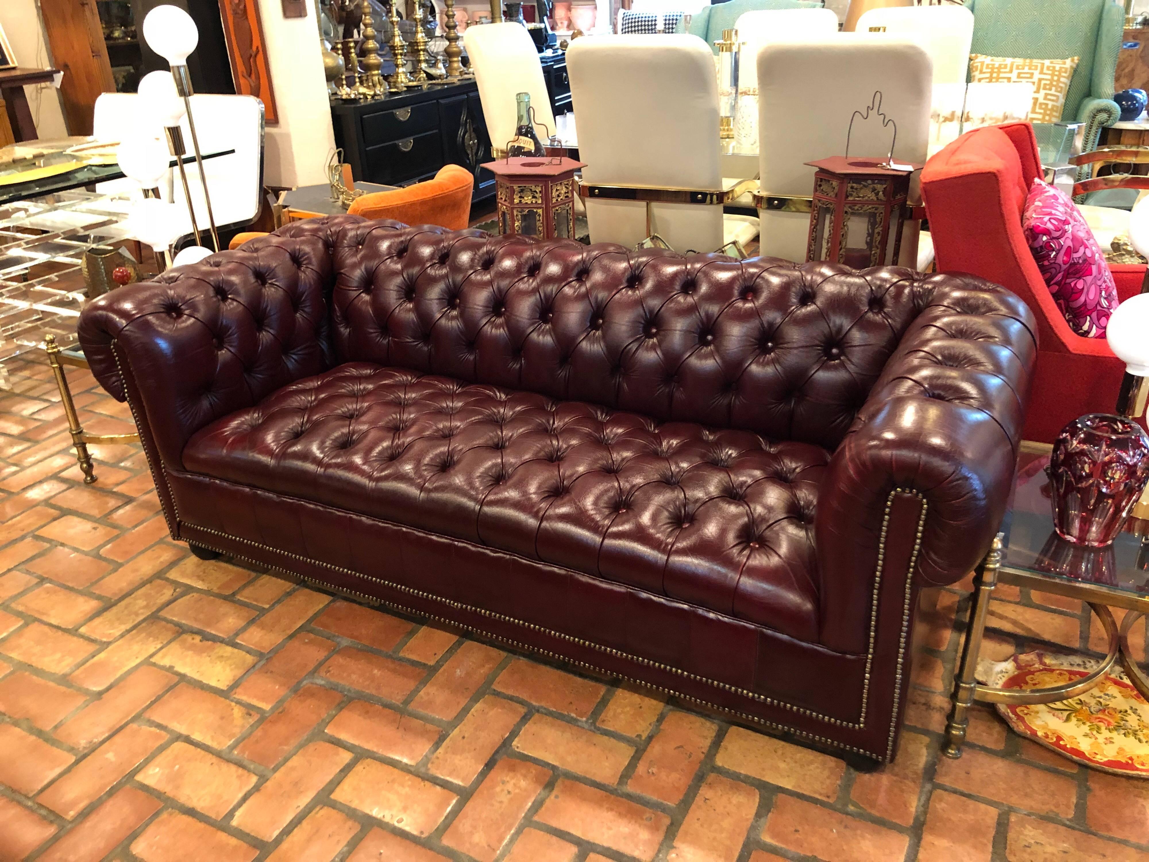 Burgundy Chesterfield sofa. Rich and luxurious, this Chesterfield is in mint condition. It would look great in any study, library or bedroom. No missing buttons or any damage. Springs are very strong and intact. Classic brass tacks surround this