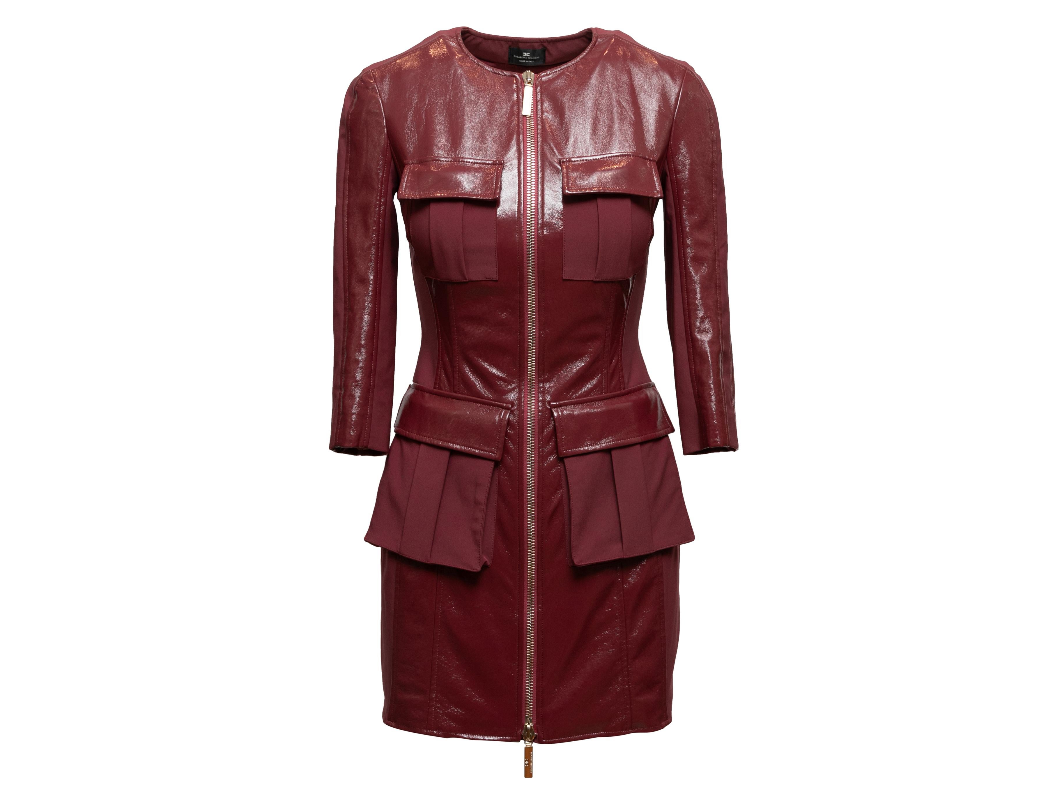 Burgundy patent Abito long sleeve mini dress by Elisabetta Franchi. Crew neck. Four pockets. Belt at waist. Open back. Exposed front zip closure. 26