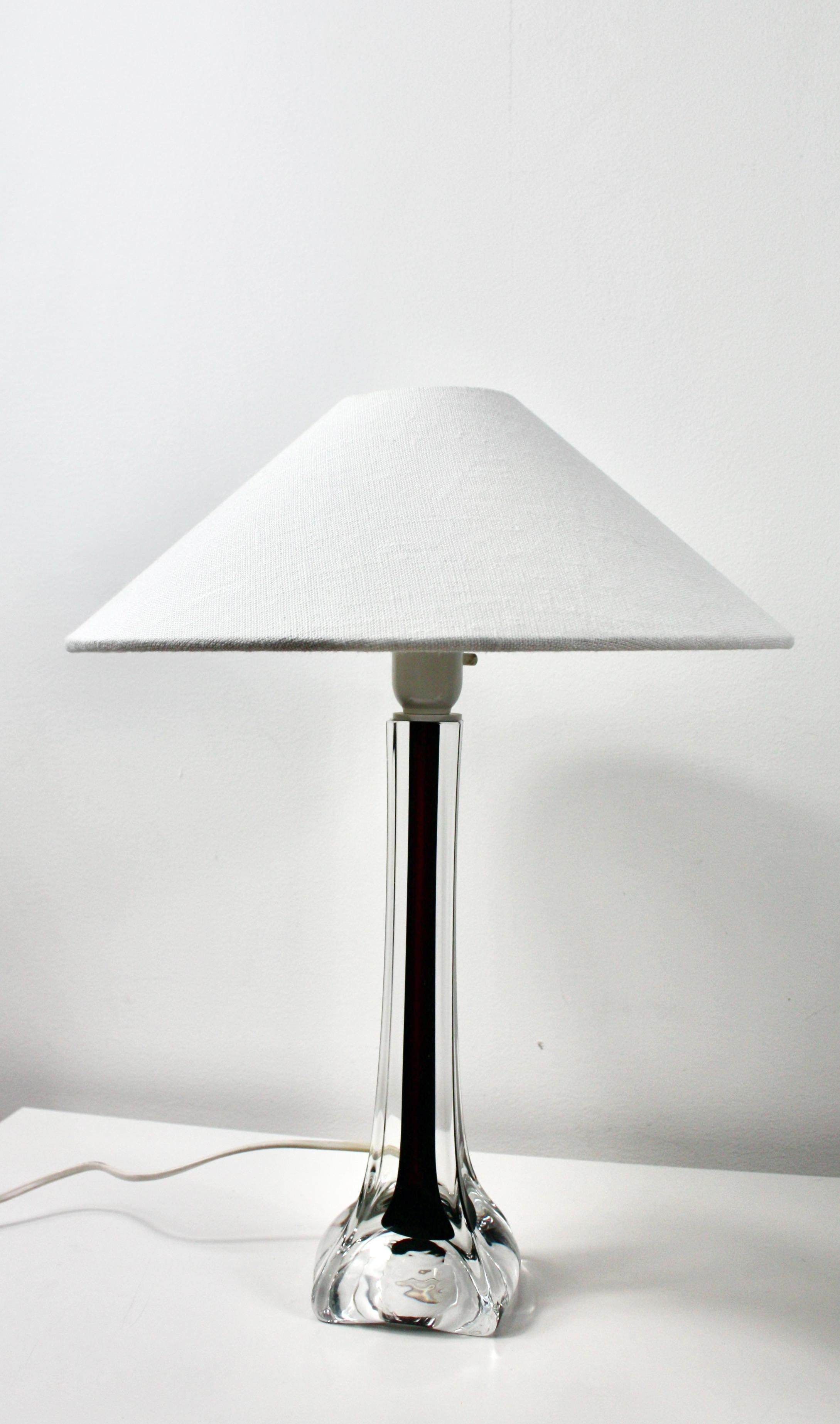 Lámpara de sobremesa vintage de cristal, diseñada por el conocido diseñador Paul Kedelv, para Flygfors, en la década de 1960.
Presenta una llamativa base de cristal burdeos y transparente. La base es elegante y esbelta, con un tallo interior de