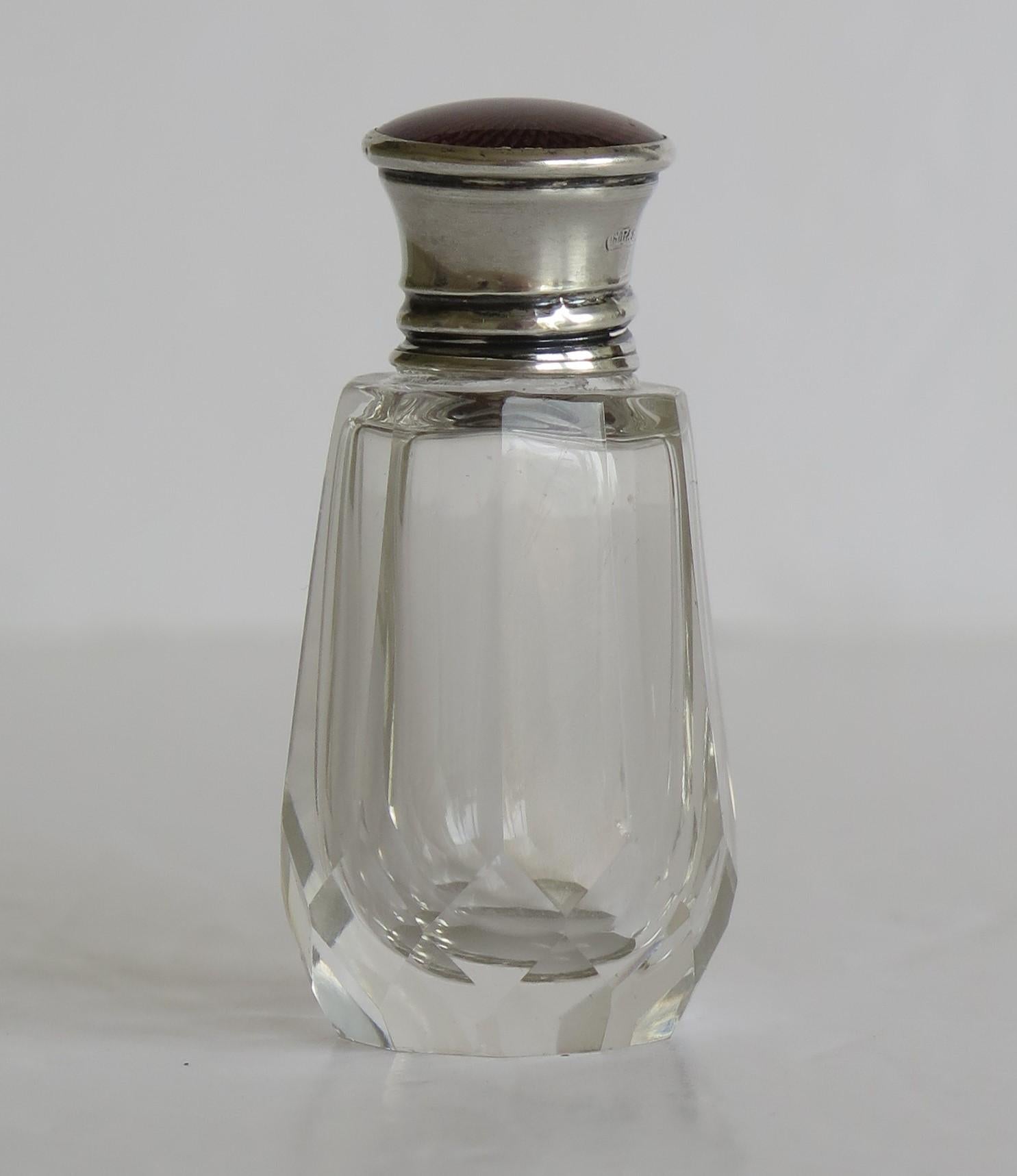 This is a beautiful scent, cologne or perfume cut glass bottle with a burgundy guilloche enamel and sterling silver topped screw top lid, 1921

The glass crystal bottle is beautifully hand cut with vertical flutes and further diamond facets around