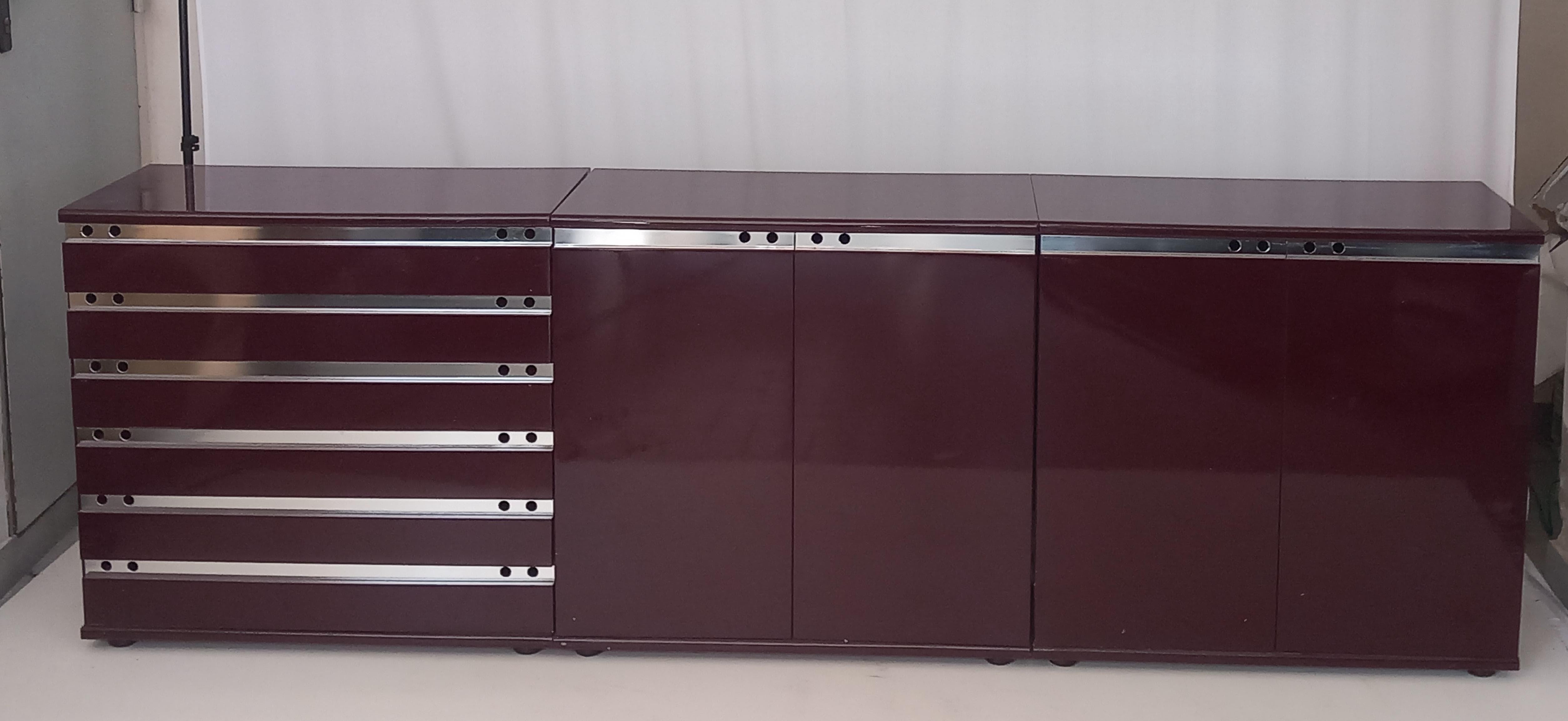 Add a touch of sophistication to any room with this stunning burgundy lacquered wood chest of drawers, designed in the 70s to combine style and practicality. Featuring chrome steel details for a modern flair, this versatile piece of furniture offers