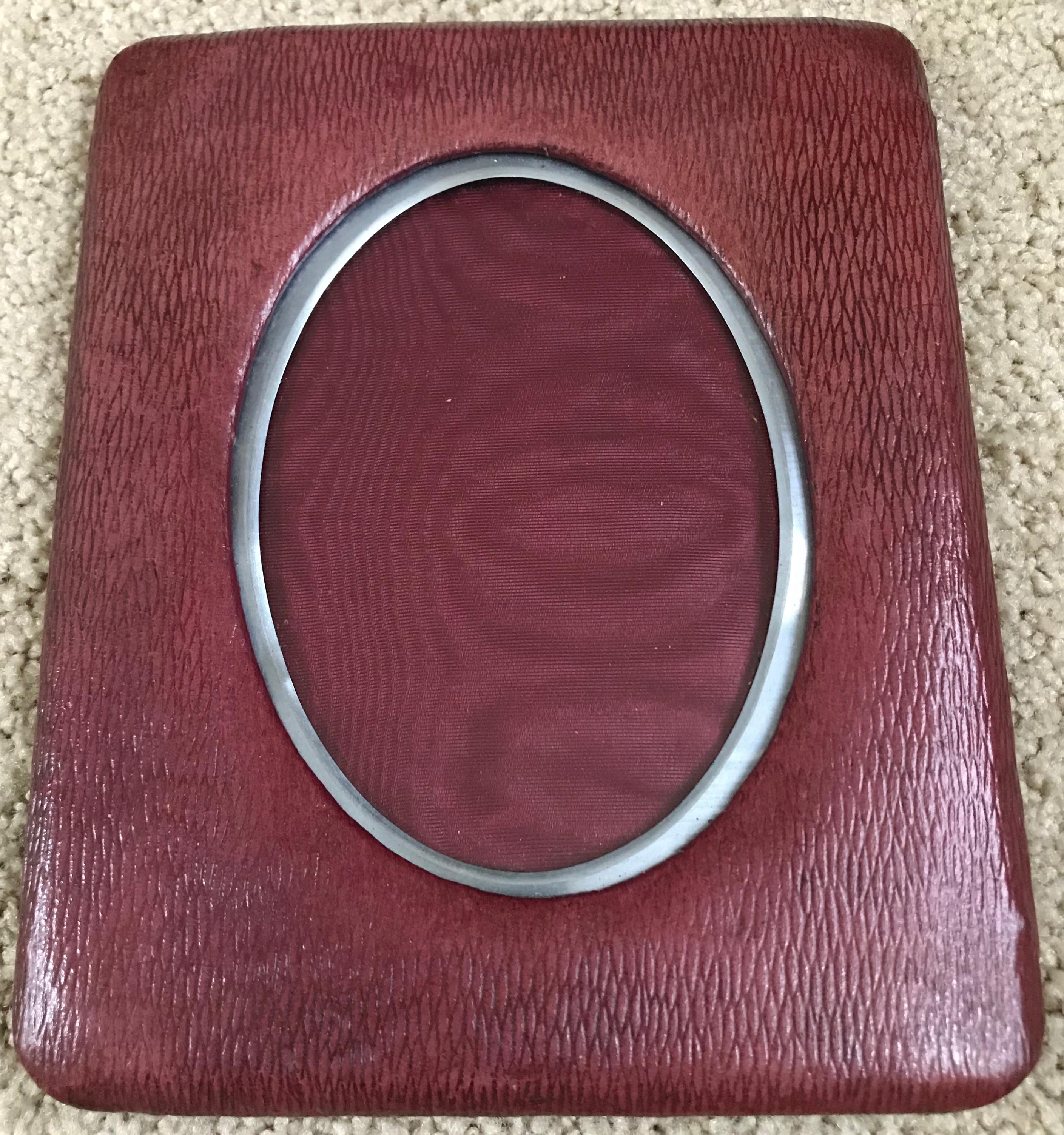 Burgundy leather and steel oval frame. Vintage English leather easel frame in rich Bordeaux burgundy textured leather with steel oval trimmed matting and black easel backing. Father's day gift, England, circa 1925.
Dimensions: 8” H x 6.5” W x 4.25”
