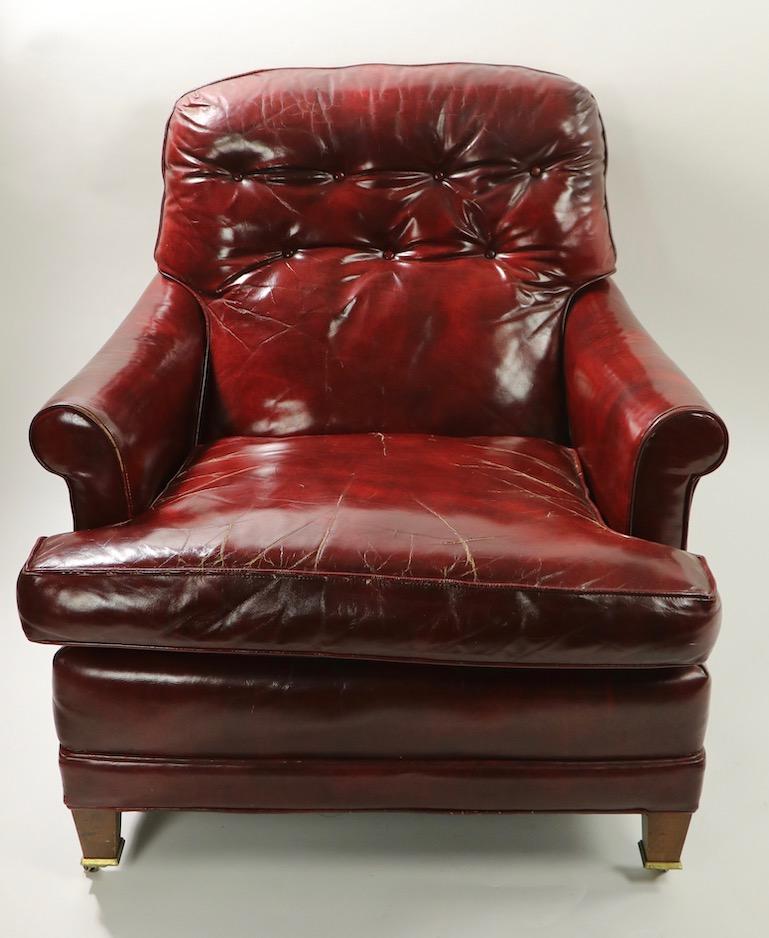 Classic English style, American made vintage leather lounge chair in wonderful vintage condition. This example features brass-mounted front wheel coasters, and stationary back feet, comfortable deep loose cushion seat, and thick padded back. Solid