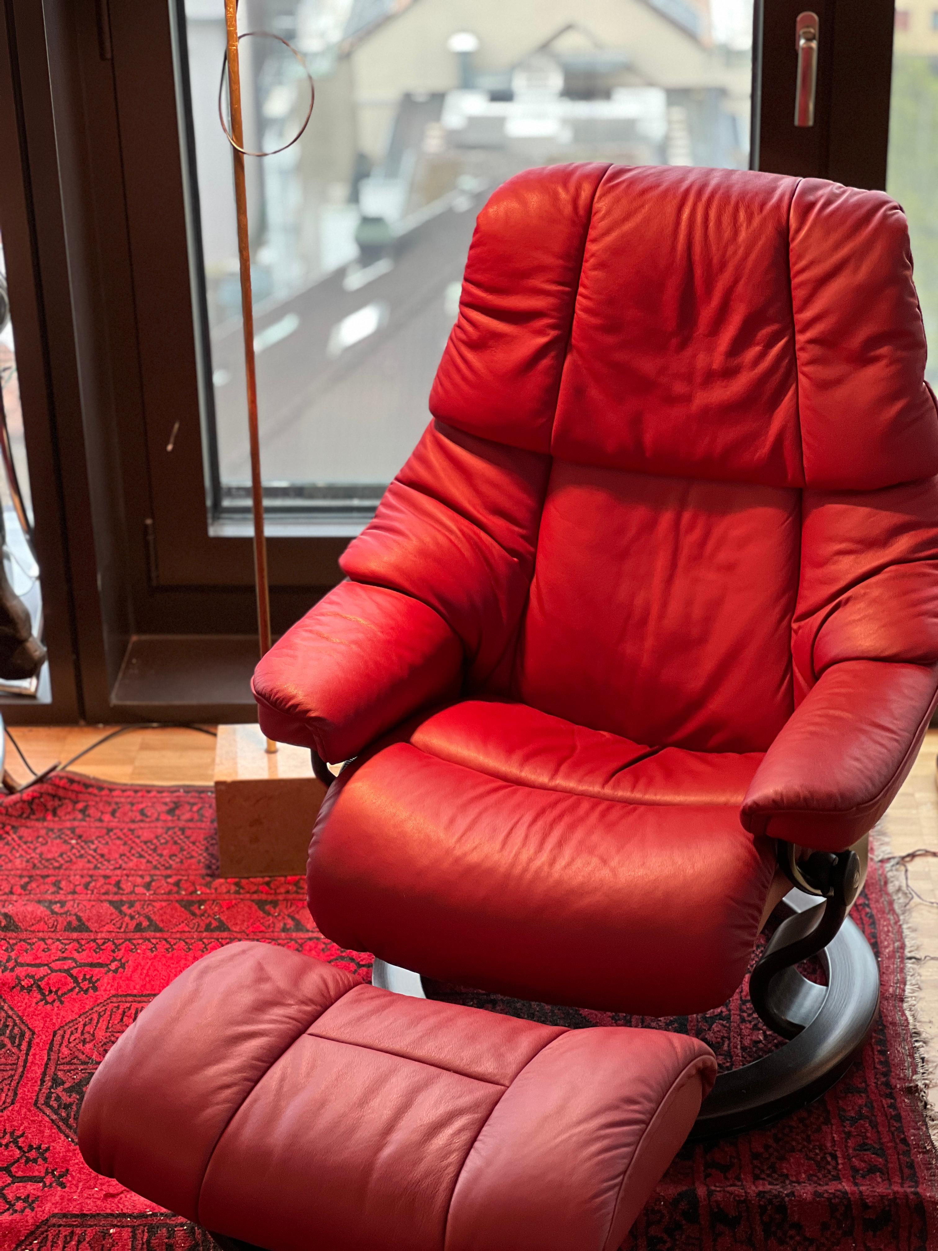A Scandinavian style recliner and ottoman by Ekornes, Norway. This chair belongs to the top line of their Stressless brand. With teak wood bases and metal frame and genuine leather upholstery, this is a comfortable burgundy color leather recliner