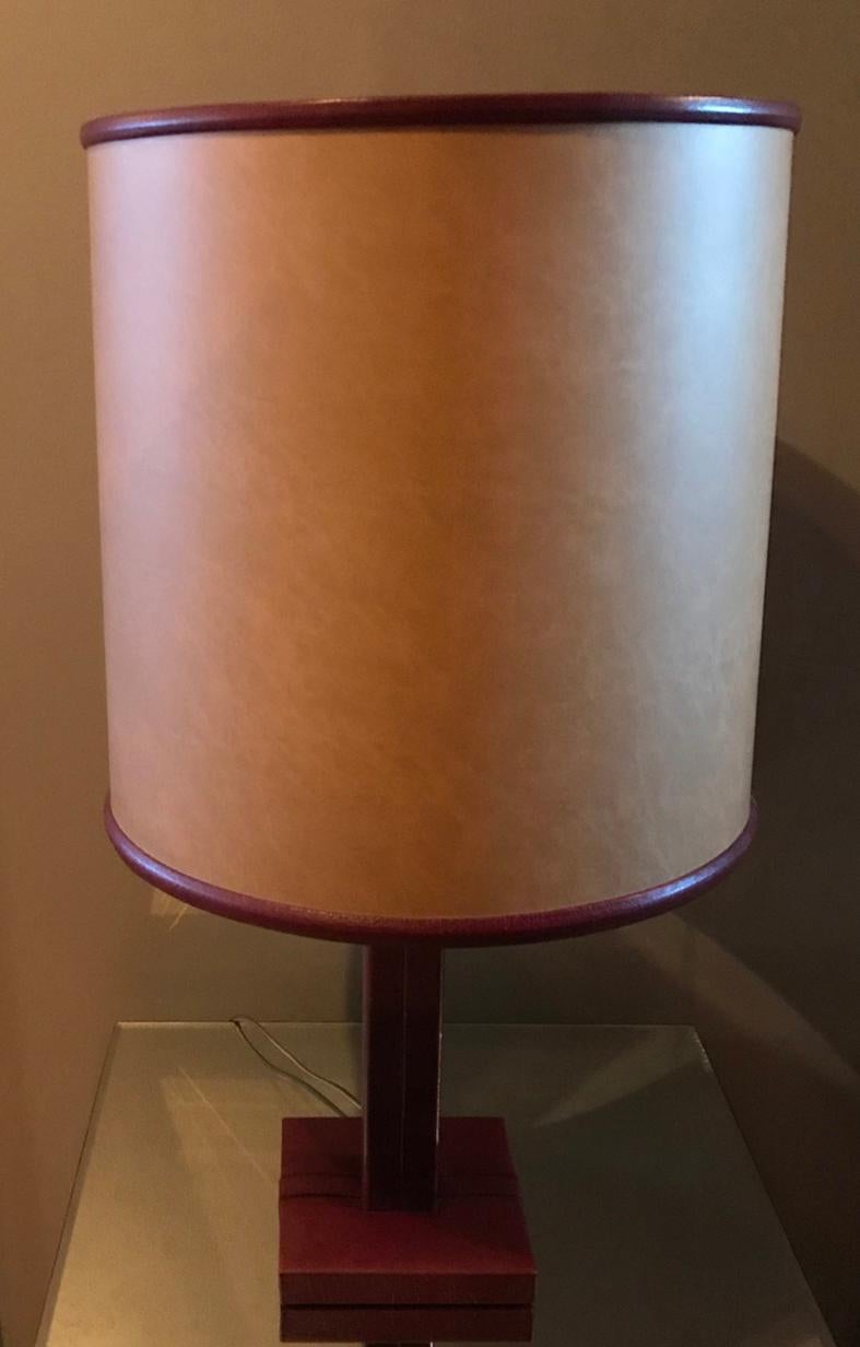 Elegant burgundy leather table lamp by Le Tanneur with a beautiful contrast black stitching detail on its base. Original parchment lampshade with its burgundy leather top and bottom frame.
Signed Le Tanneur.

Dimensions :
Total height with its