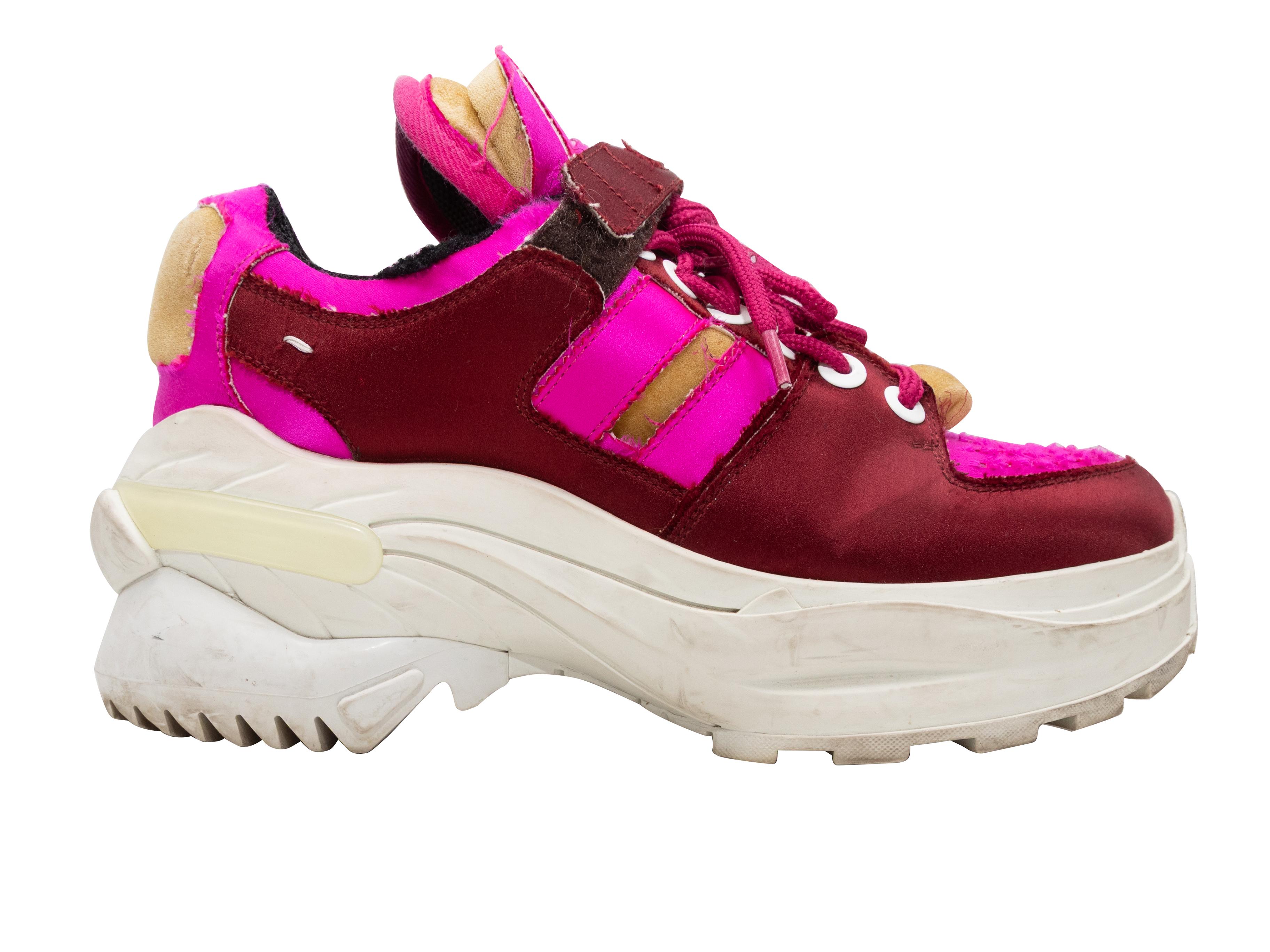 Burgundy, tan, and hot pink satin chunky distressed low-top sneakers by Maison Margiela. Rubber soles. Lace-up and velcro strap closures at tops. 1.75