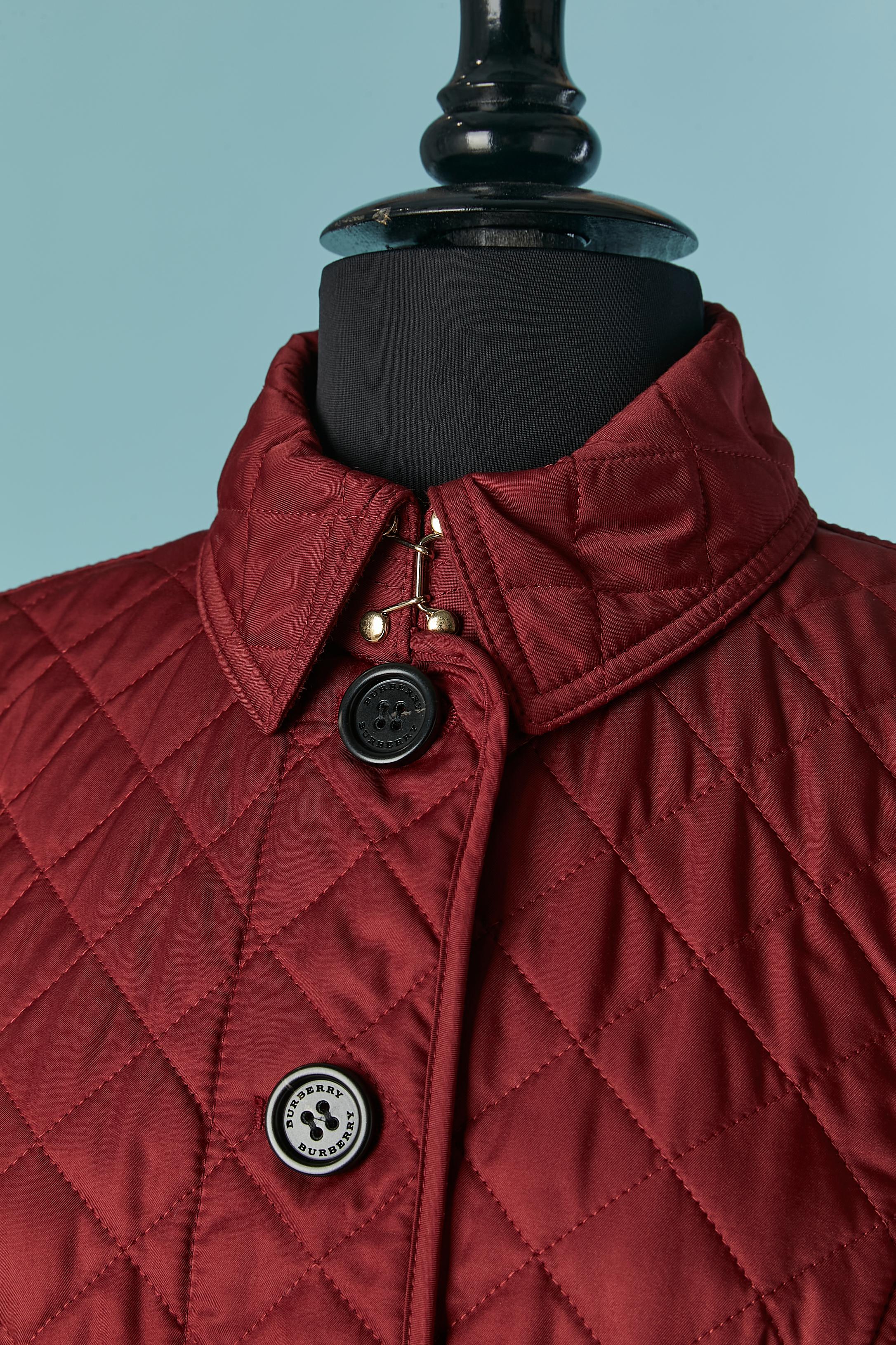Burgundy single-breasted quilted jacket. Shell composition: polyester. Lining: polyester. Linning's panels: cotton. Filling: polyester. 
Branded button and buttonhole on the middle front. 2 splits on the back with branded gold metal snaps. 
SIZE M 