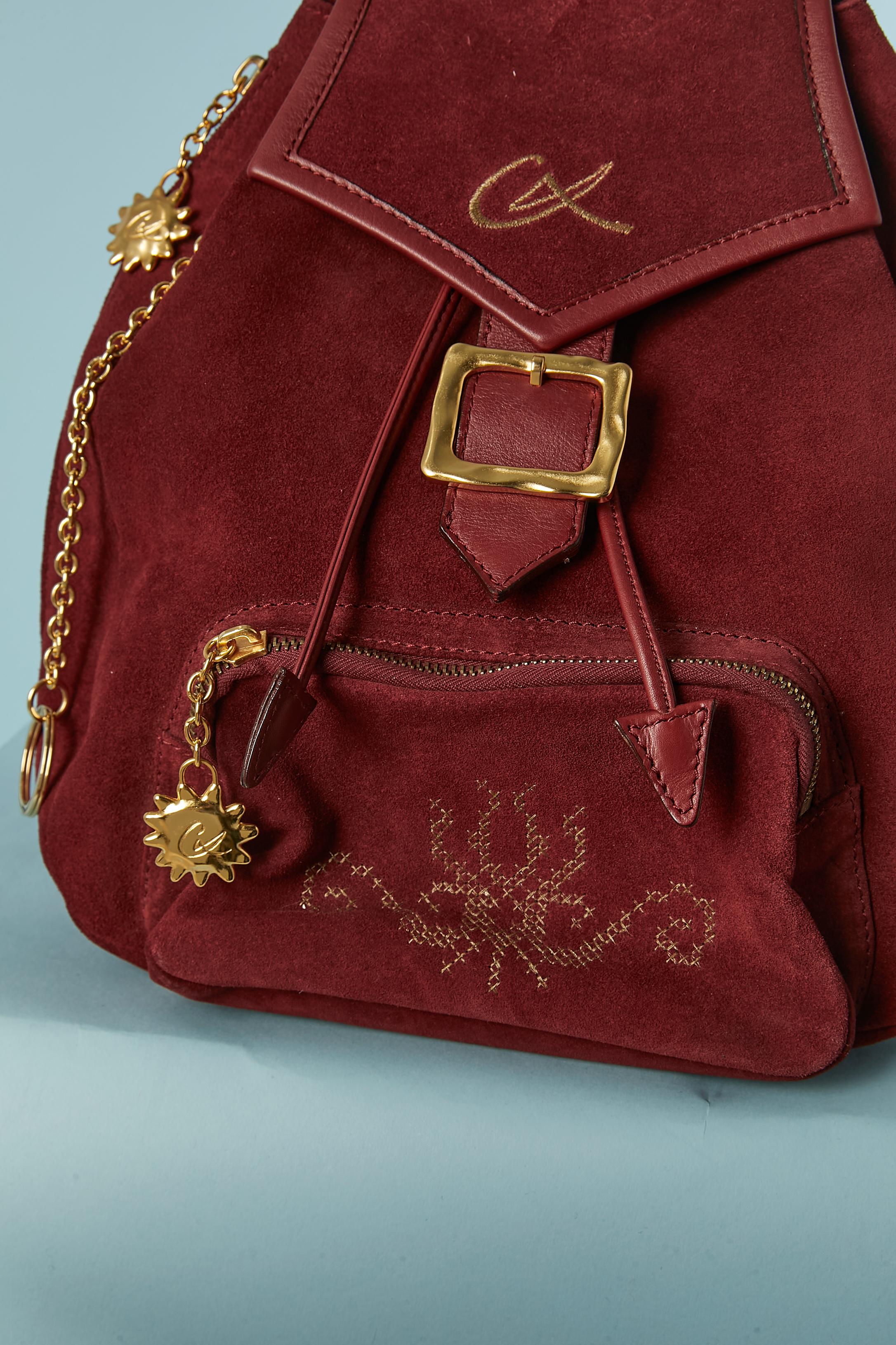 Burgundy suede back-pack bag with front pocket . Faux suede yellow lining inside. One pocket with zip inside. Adjustable shoulder strap. Gold metal decorative buckle with snap closure underneath. 
Leather drawstring closure on the top with metal