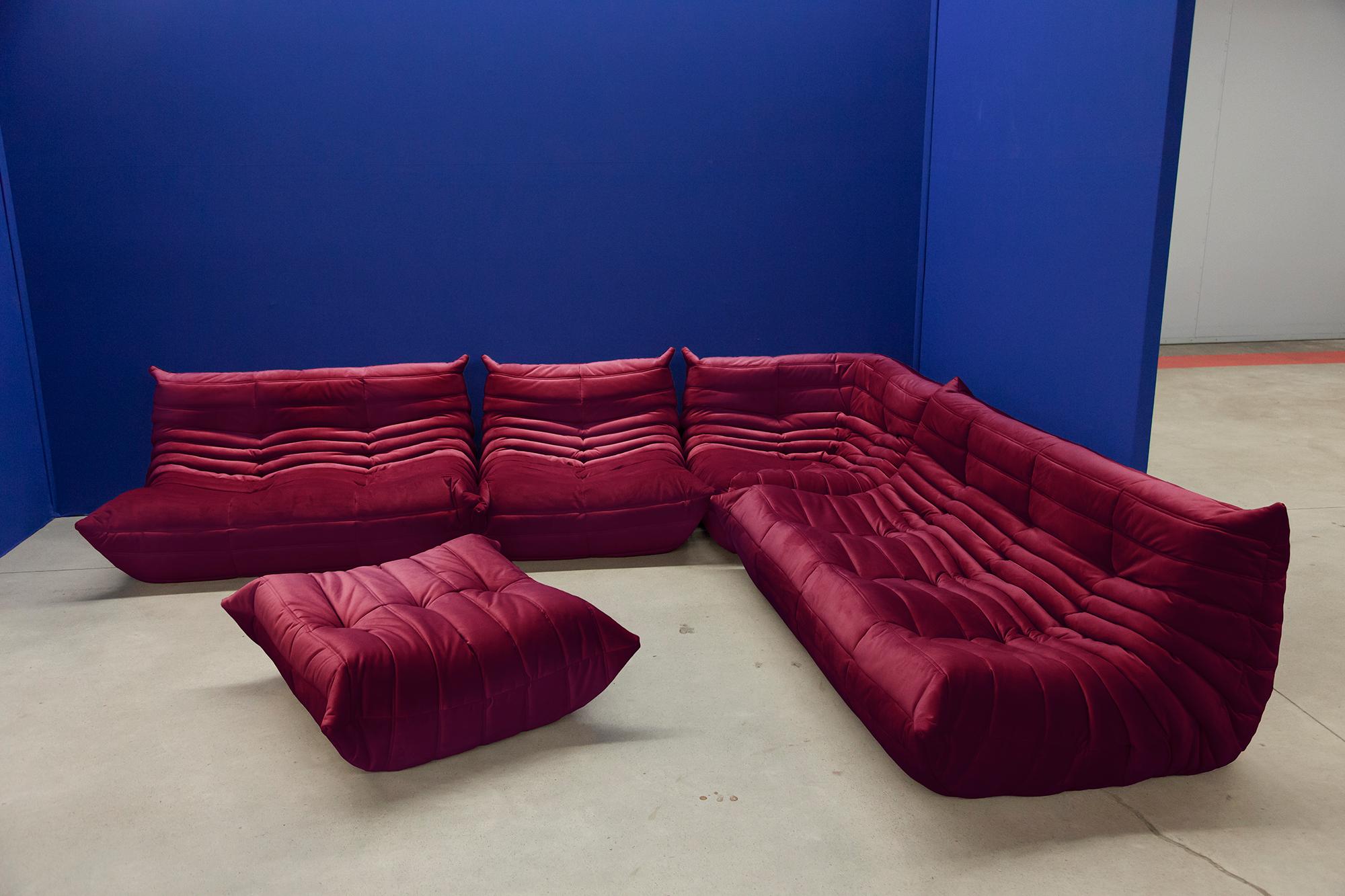 This Togo living room set was designed by Michel Ducaroy in 1974 and was manufactured by Ligne Roset in France. Each piece has the original Ligne Roset logo and genuine bottom. It has been reupholstered in genuine high quality burgundy red velvet