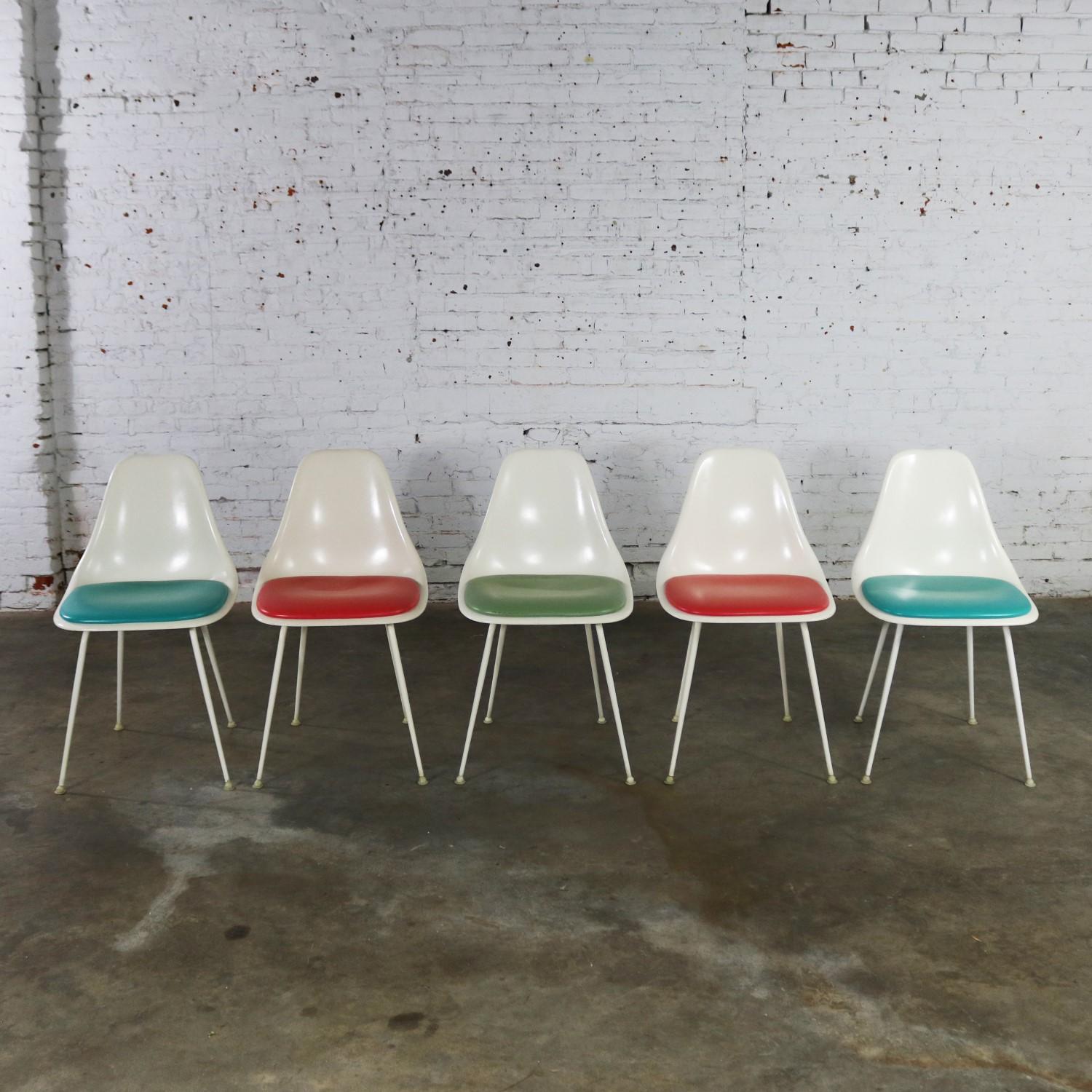 Awesome set of five mid-century modern Burke #103 fiberglass shell side chairs with multicolored vinyl padded seats in turquoise, coral and green. They are in wonderful vintage condition apart from one turquoise chair which has a cut in the original